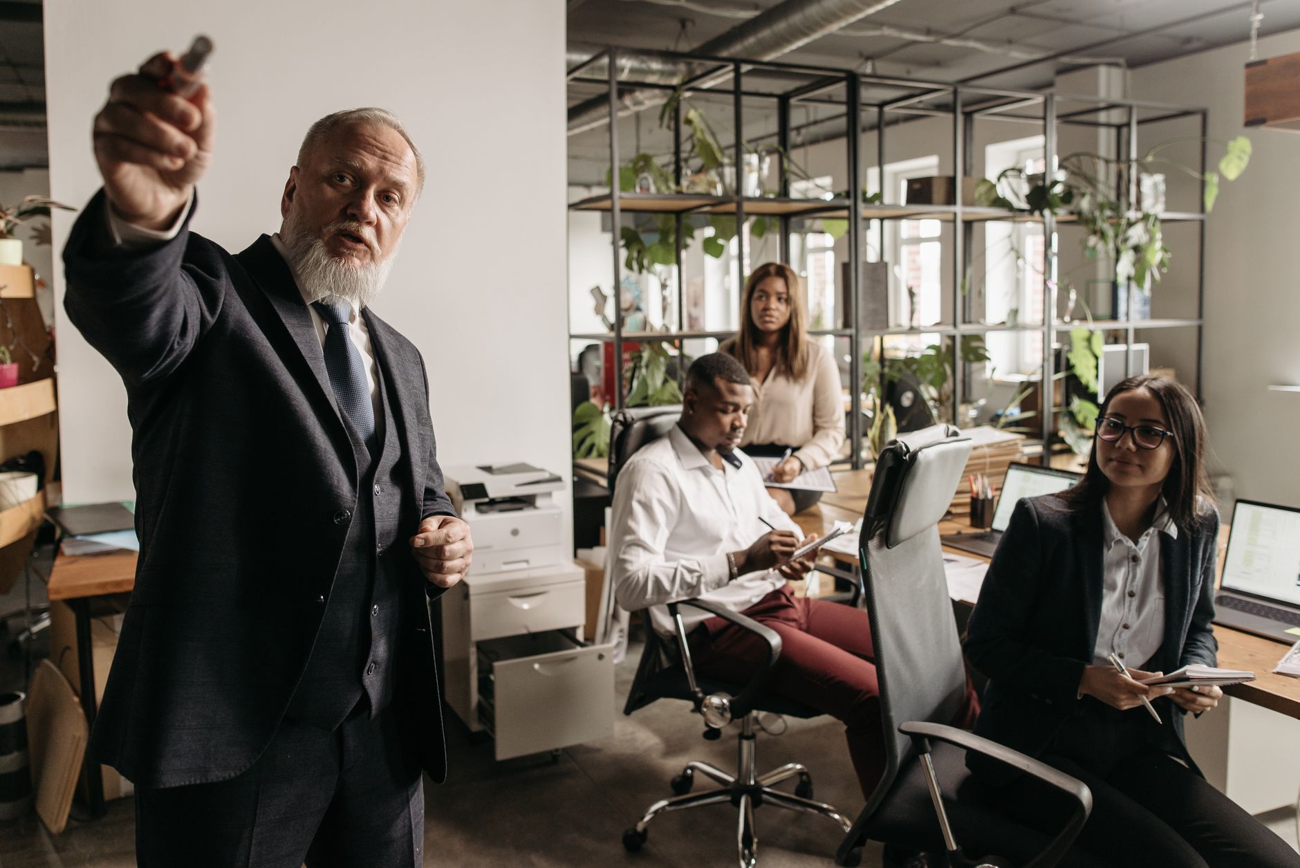Personal Leadership Development as a Strategic Manager — A diverse team in a modern office setting engaged in a business meeting with a senior leader presenting.