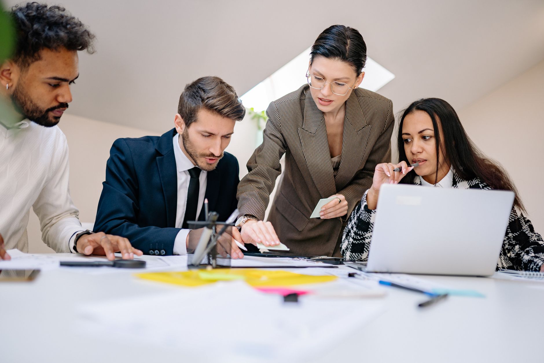 Strategic Planning in Cross Border and Global Organisations — Business team working together at desk with documents and laptop in a contemporary office.
