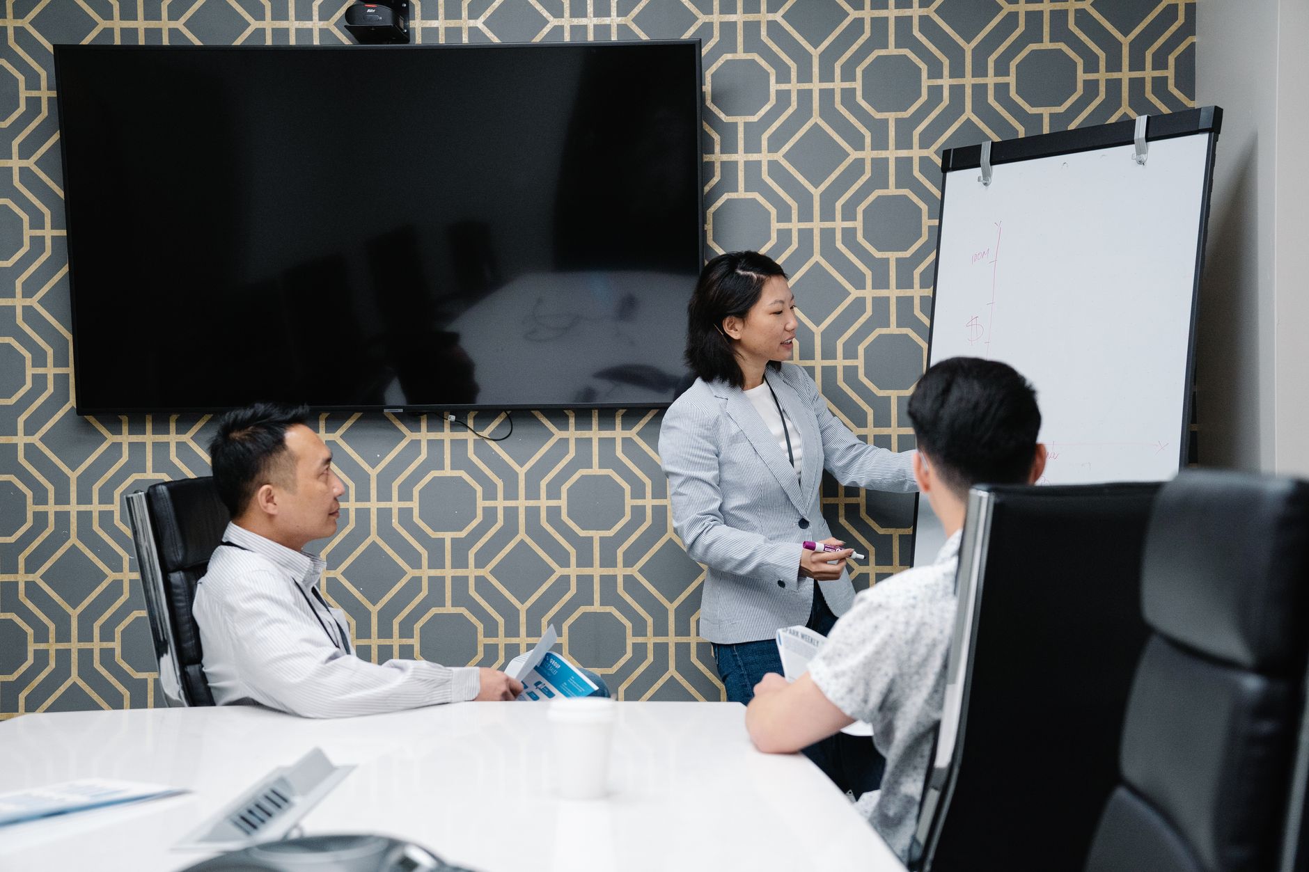 Strategic Direction in Cross Border and Global Organisations — A professional conducting a presentation in a modern office space with colleagues engaged.