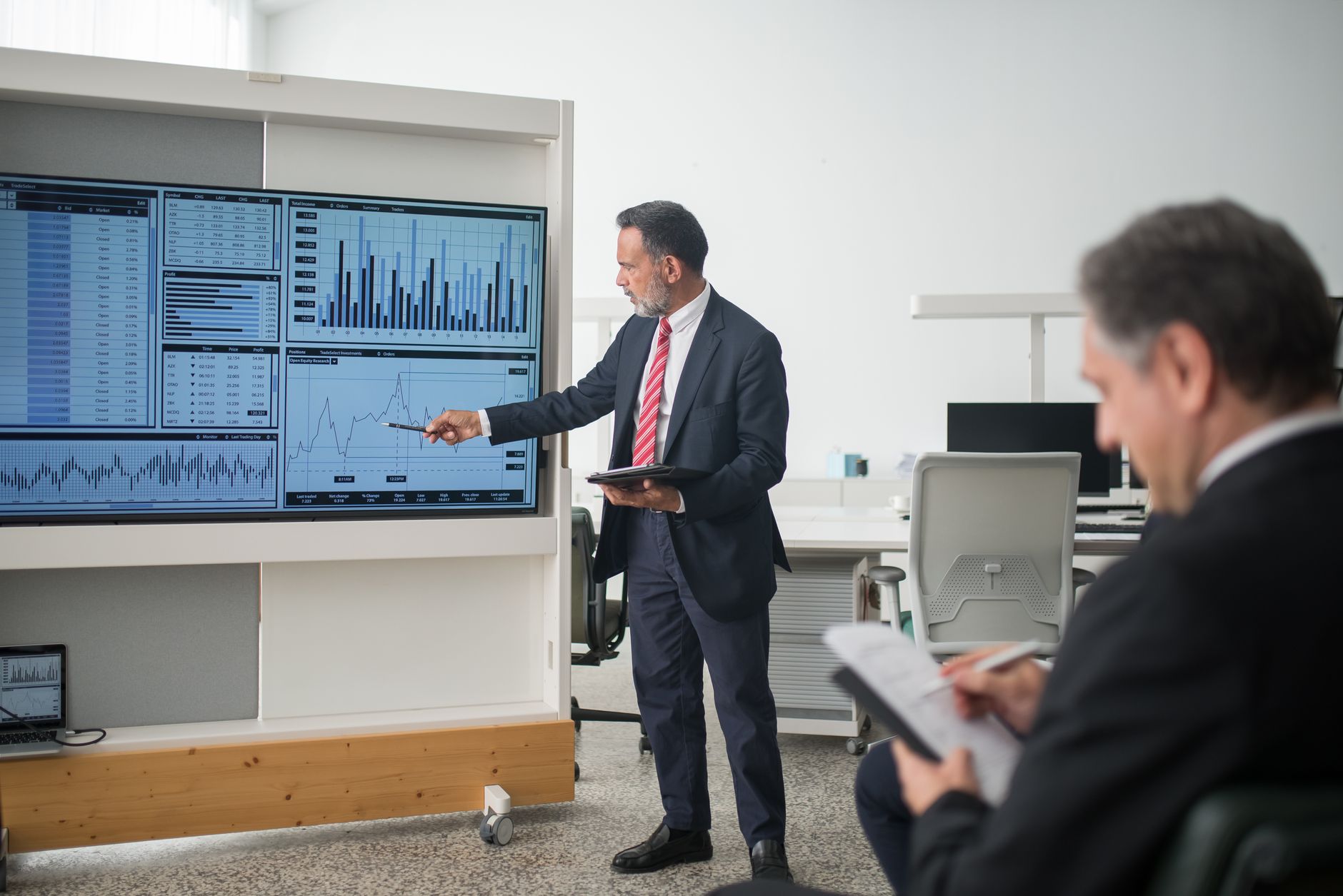 Consumer Behaviour and Market Communications — Professional conducts data analysis presentation in a modern office setting.