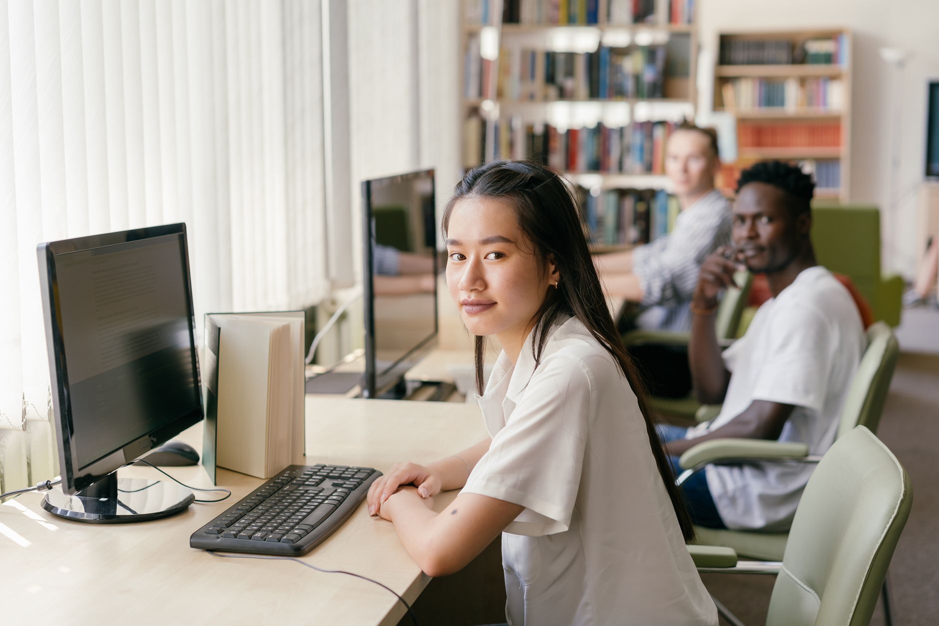 Equality, Diversity, Inclusion, and Human Rights — Students engaged in learning at a modern library with computers and natural lighting.