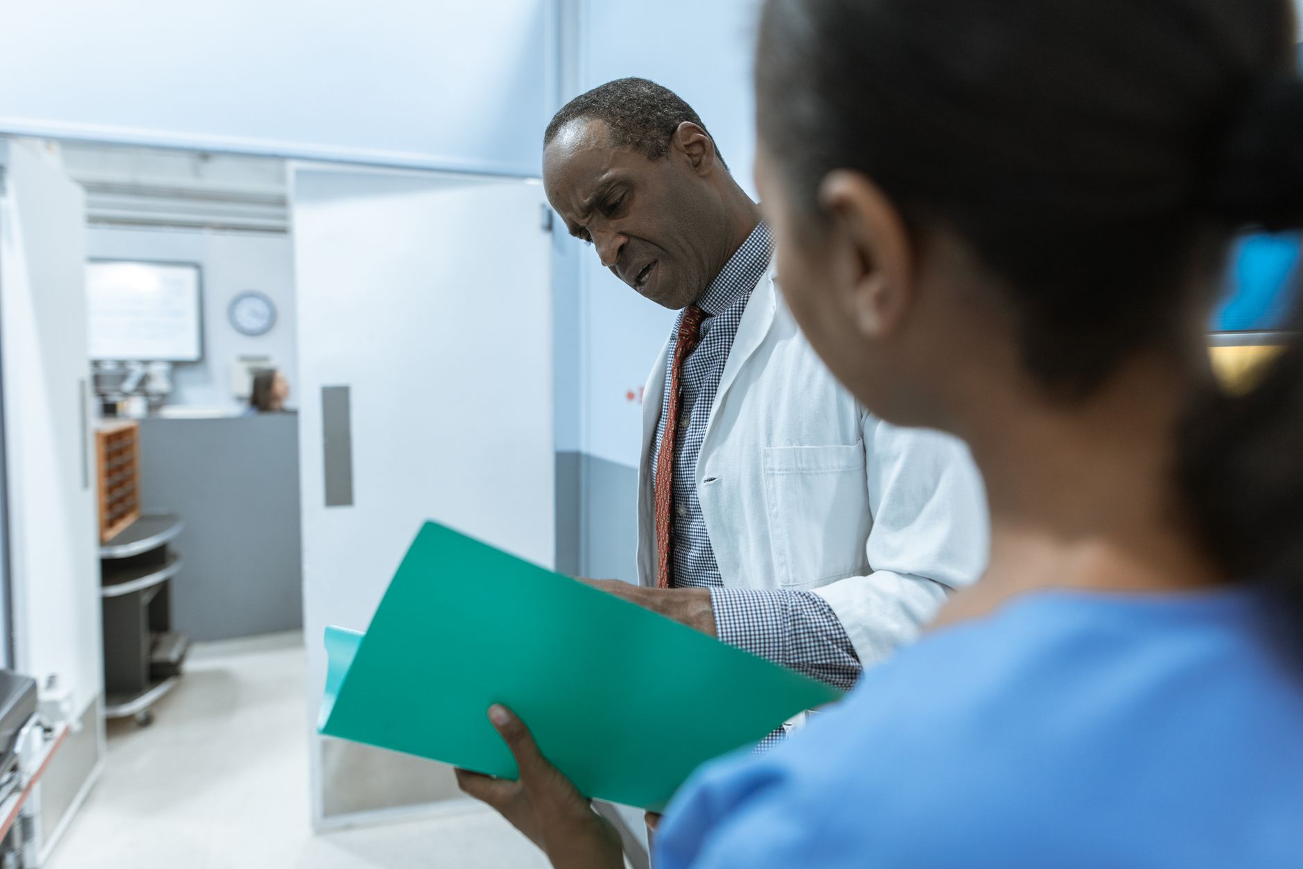 Handling Information — Doctors examining a folder in a hospital setting, highlighting teamwork and healthcare professionalism.