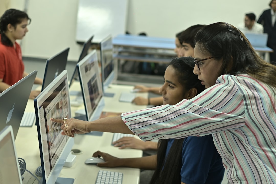 An Awareness of Learning Disability and Autism — Teacher guiding students on computer in classroom.