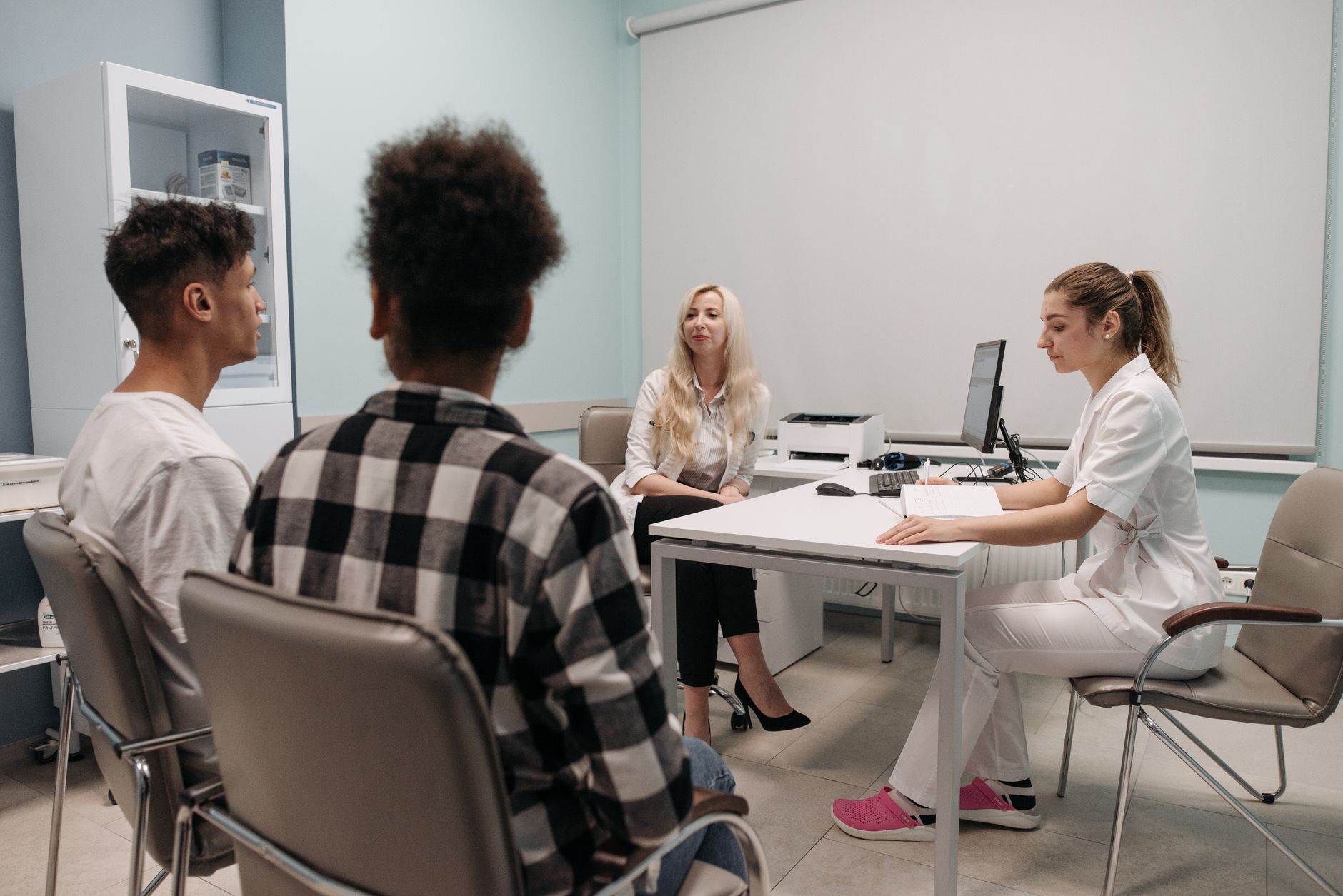 Communication for Health and Social Care — Doctors talking with patients during a medical appointment in a clinic office setting.