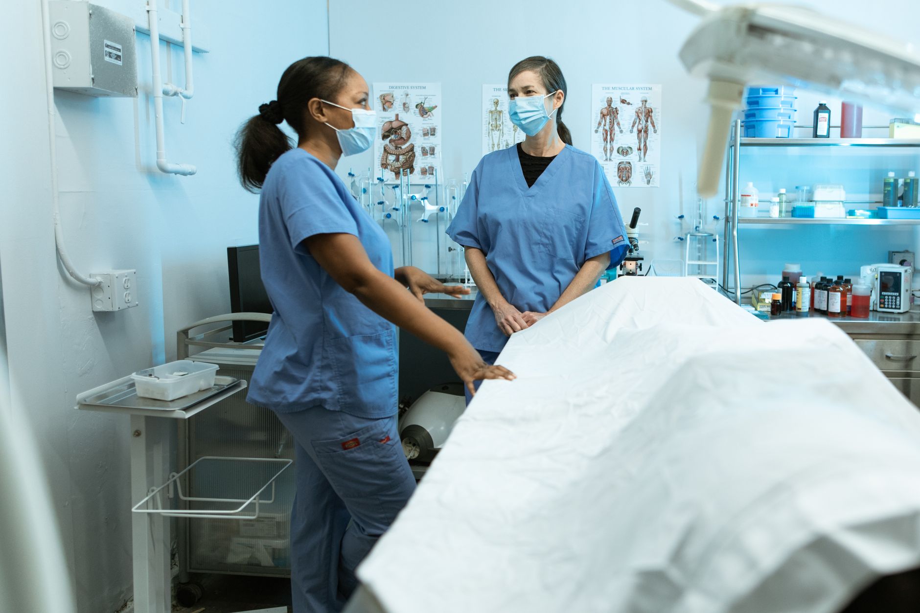 Reflective Practice — Medical professionals in scrubs and masks discussing in a clinical environment.