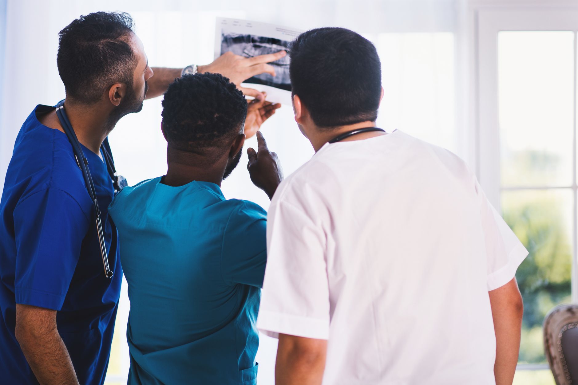 Partnership working in Health and Social Care — Doctors collaboratively analyzing an x-ray in a clinical setting, showcasing teamwork and medical expertise.
