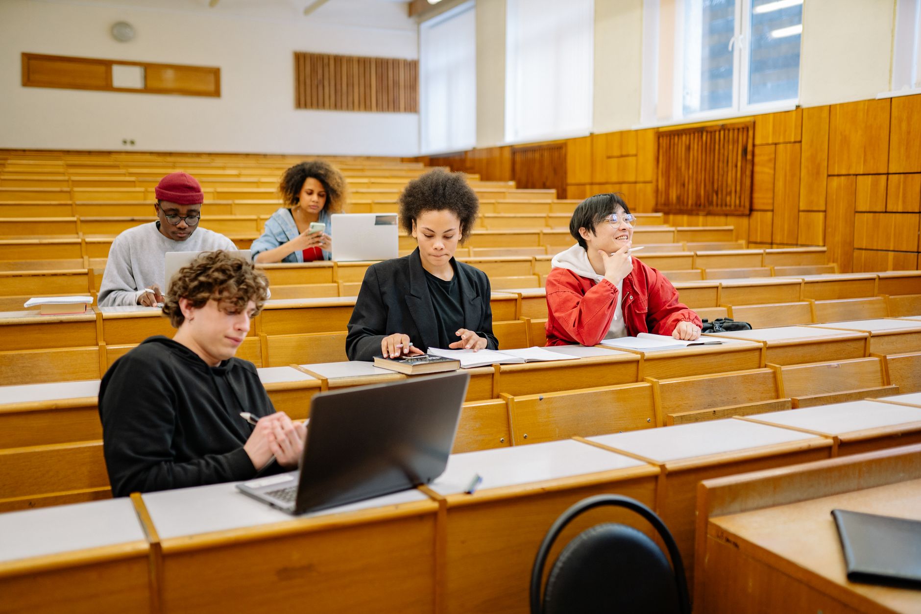 Academic Study Skills — Group of college students studying together in a classroom, focused on learning with laptops and books.