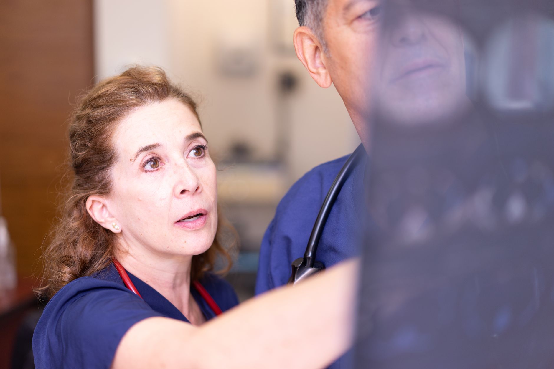Principles Underpinning Health and Social Care — Doctors in scrubs examining an x-ray in a clinical setting for diagnosis.