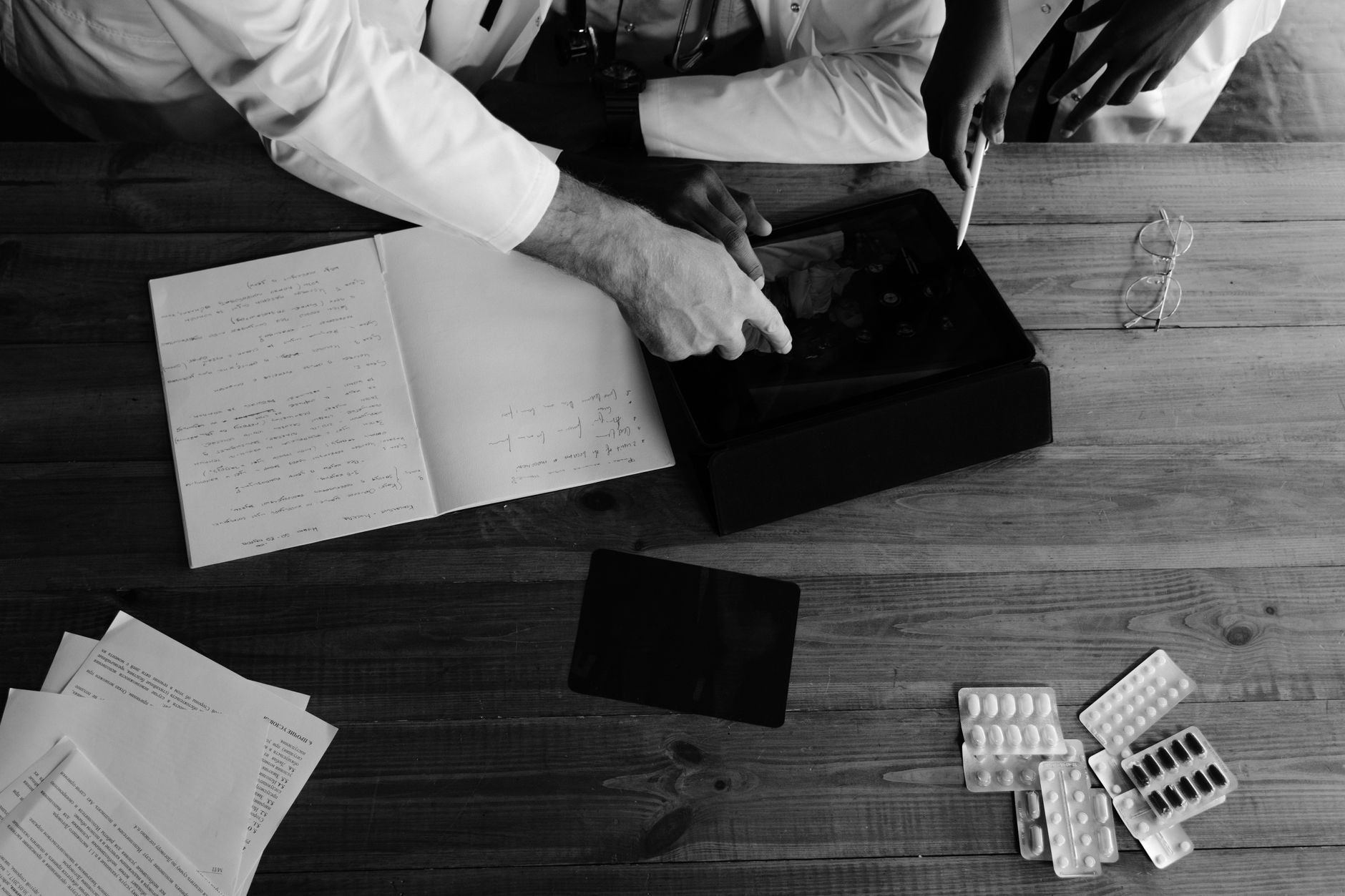 Research Project — Doctors collaborating on medical research using tablets and notebooks in a monochrome setting.