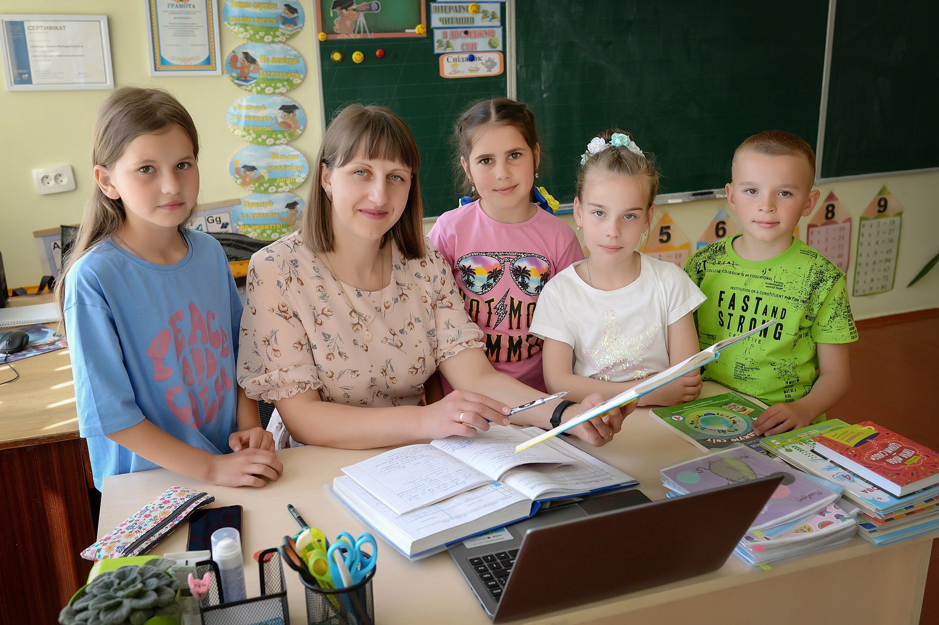 The Development of Psychological Attachments — A teacher with four students in a classroom encouraging education and learning.