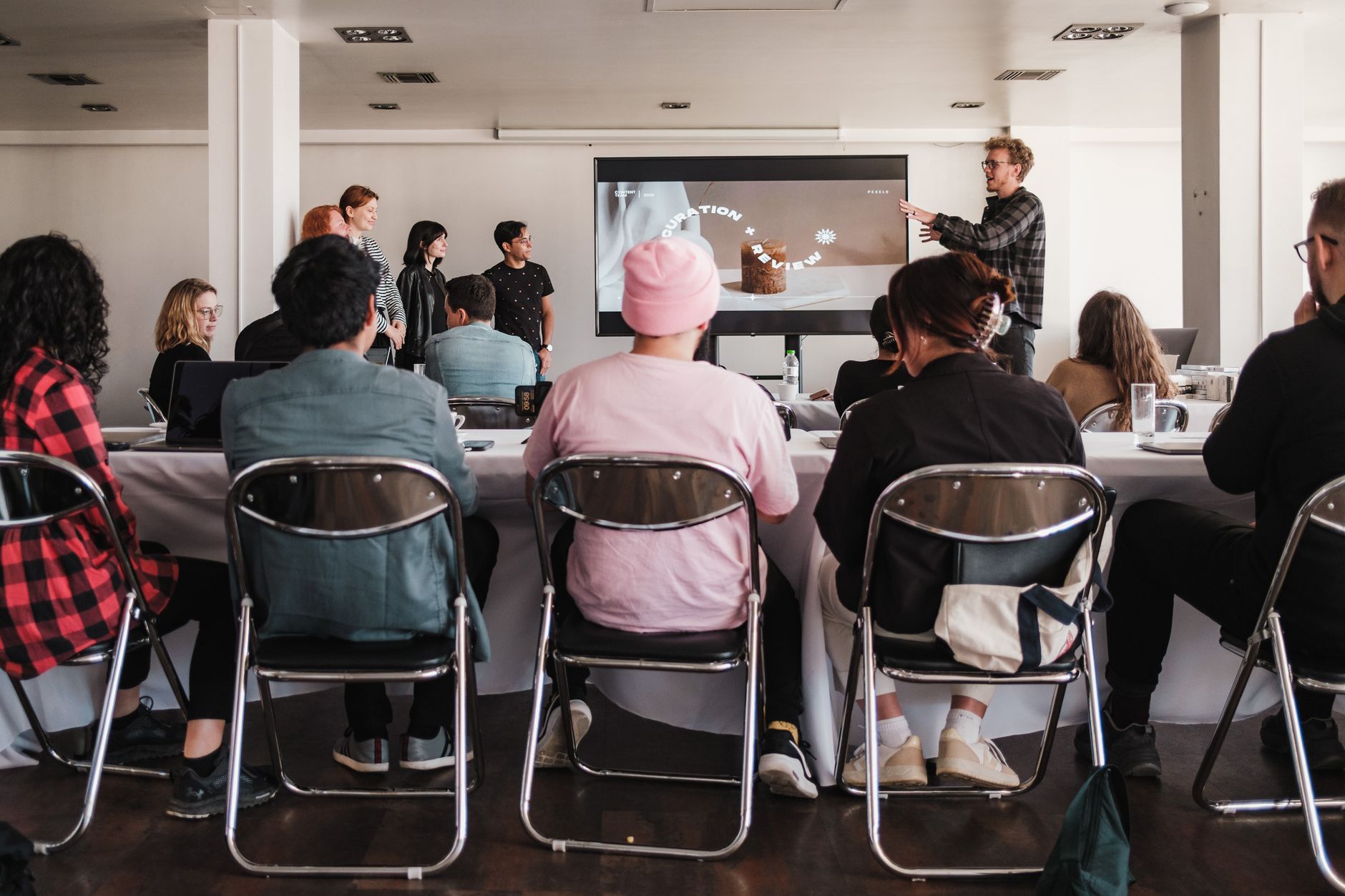 Visual Perception in a Psychological Context — A diverse group engaged in a business workshop with a presentation screen; professional learning setting.