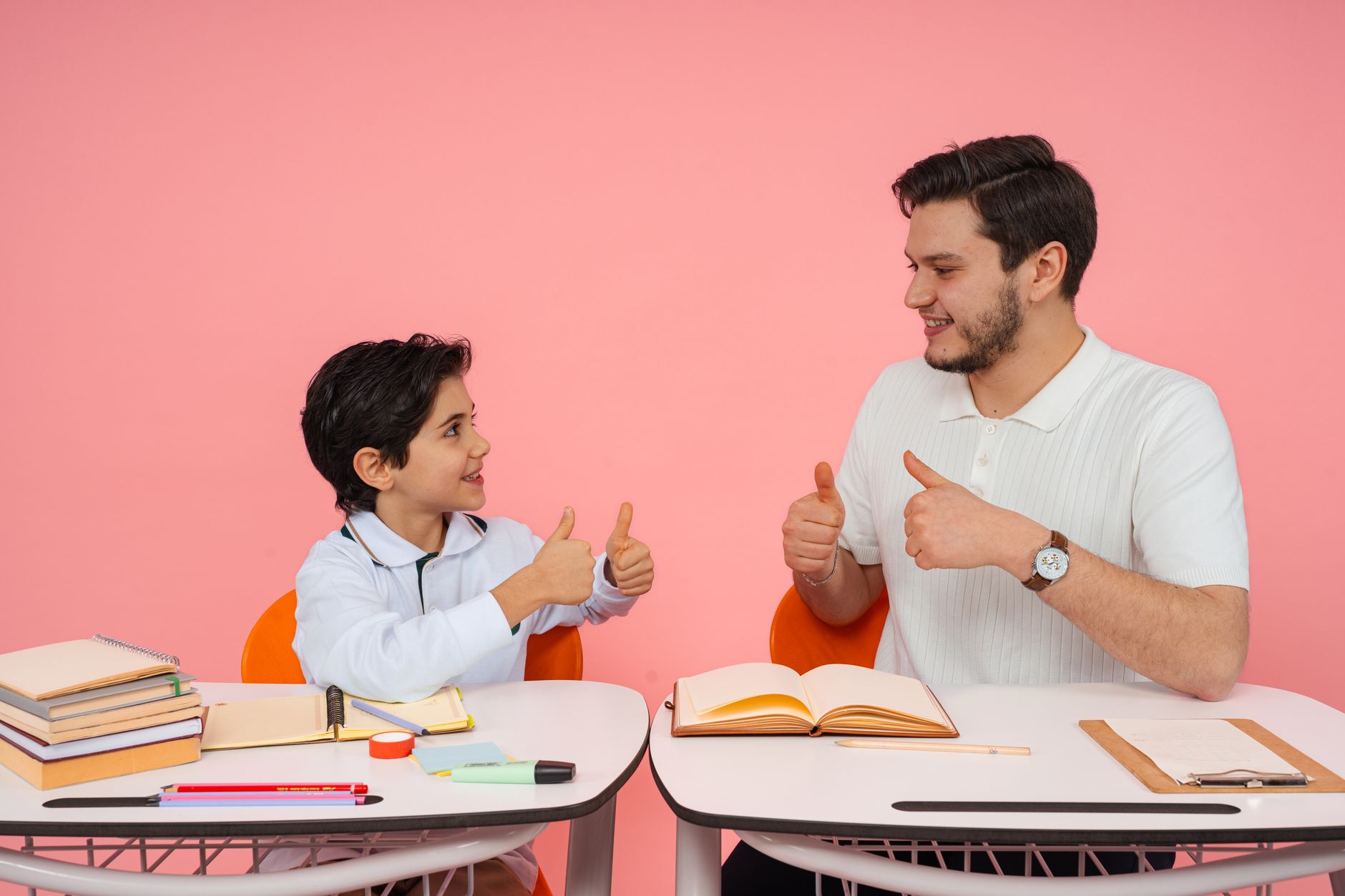 Exploring psychology — Teacher and student exchanging thumbs up at desk in a learning environment.