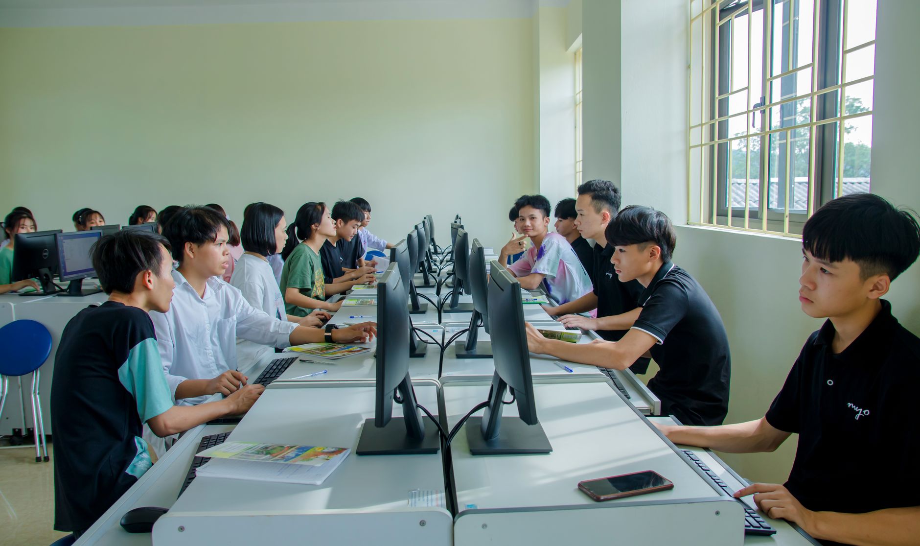 Strategic Commitment to Health and Well-Being — Diverse group of students studying in a computer-equipped classroom setting.