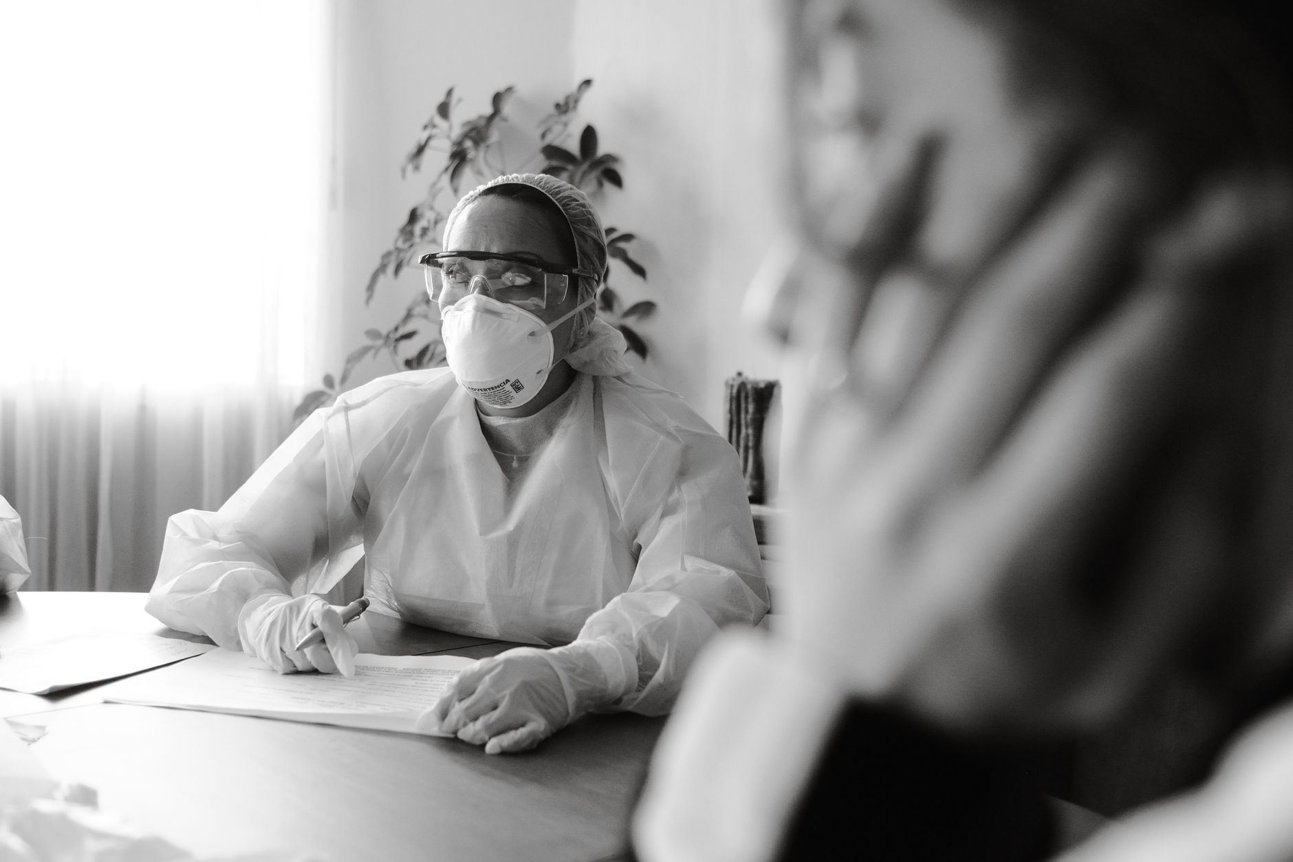 Management-Driven, Risk-Based Safety Management Systems — Medical professional in ppe conducting a consultation in a clinical setting.