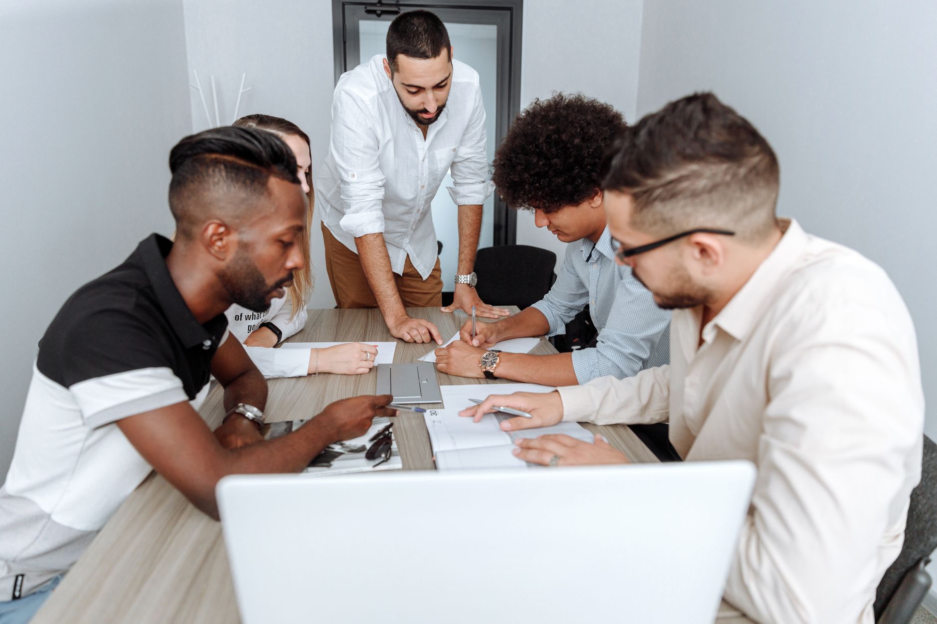 Development as a Strategic Manager — A diverse group of professionals actively collaborating at an office table during a business meeting.