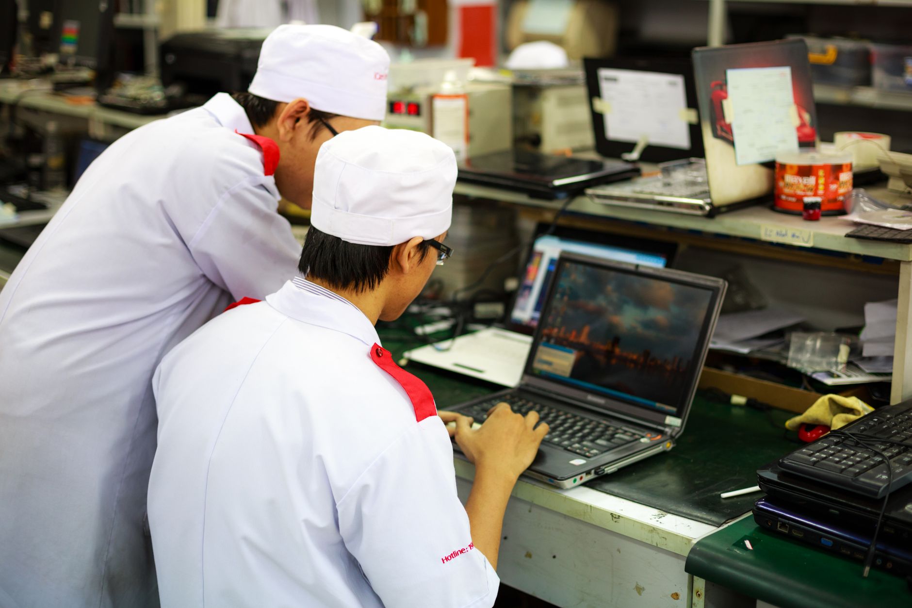 Introduction to the Hospitality Industry — Two technicians in uniforms working on laptops in a laboratory setting. focus on teamwork and technology.