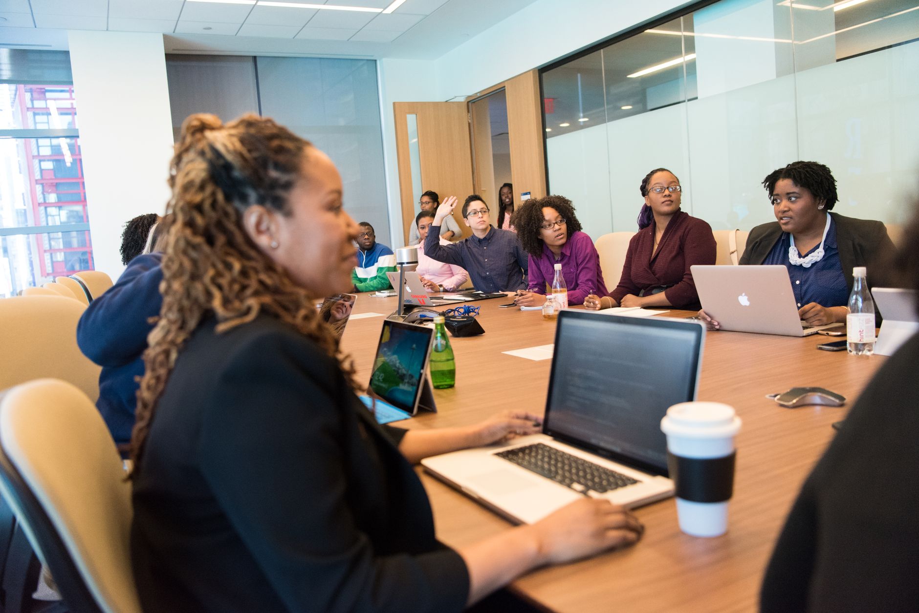 Entrepreneurship in Tourism and Hospitality Management — A diverse group of professionals engaging in a team meeting with laptops and discussions in a modern office setting.