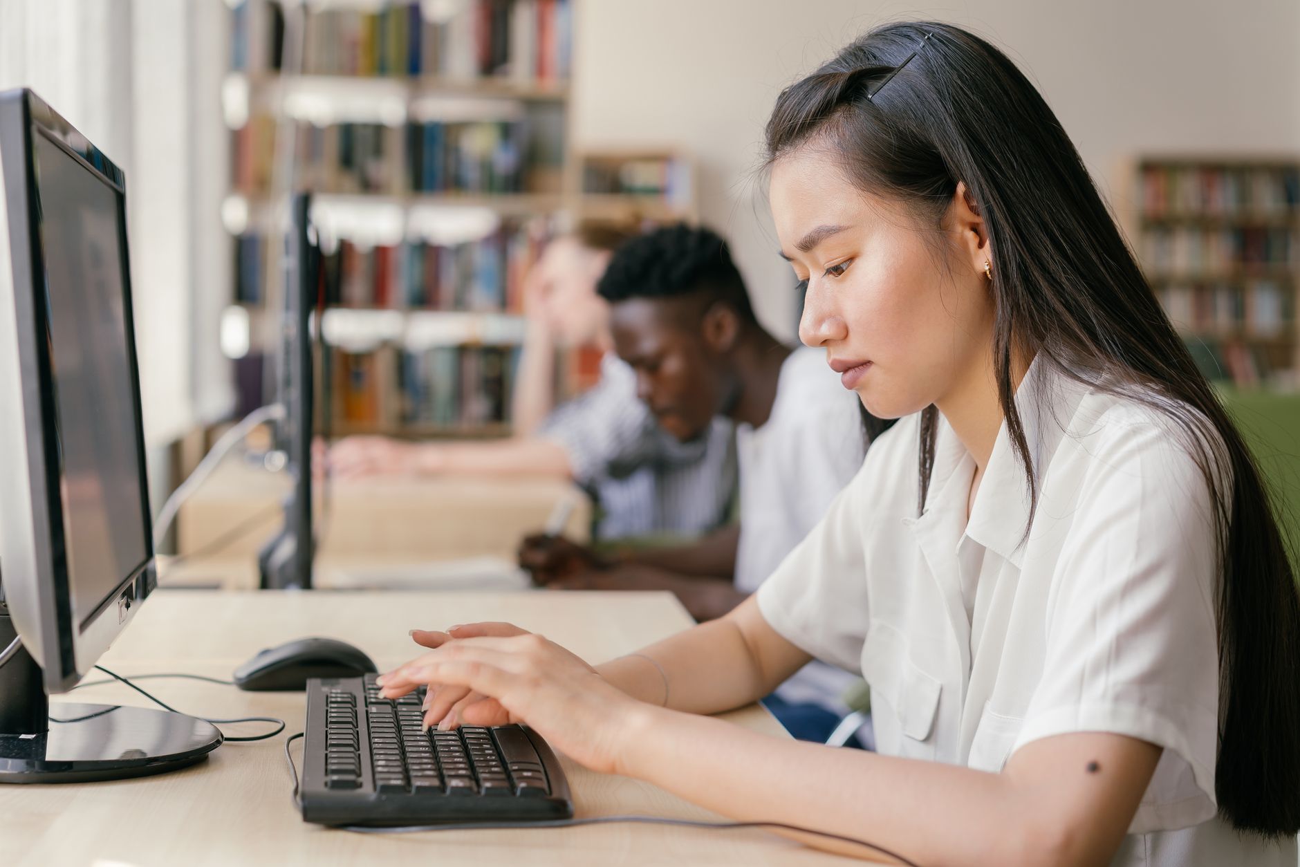 Research Project — Students using computers in a library, focused on academic research and learning.