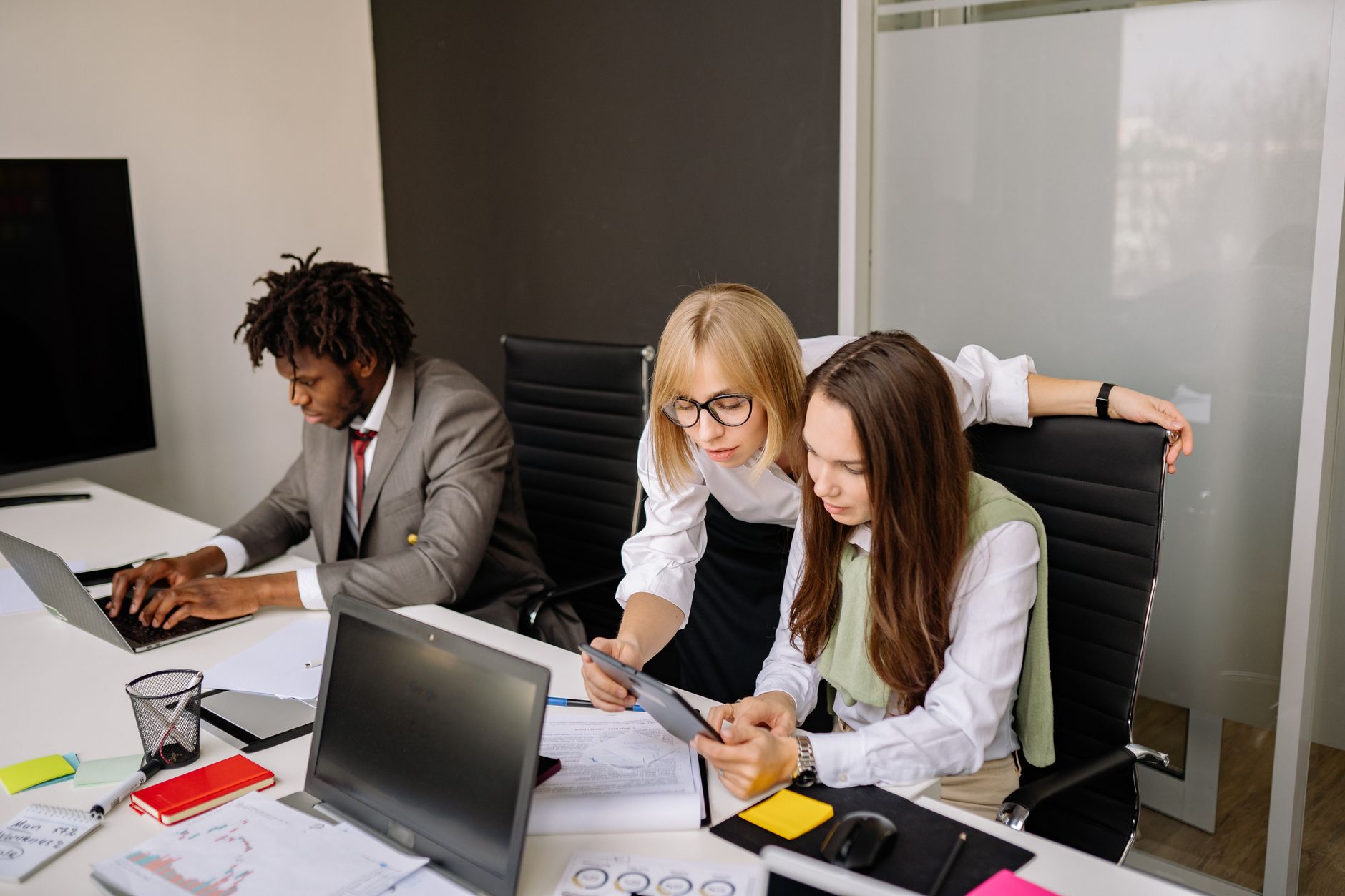Entrepreneurship in Tourism and Hospitality Management — Business team collaborating in a modern office setting with laptops and tablets.