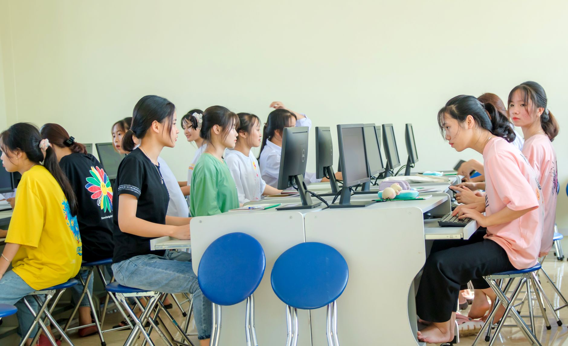 The Culture and Society in Tourism — Students in a computer lab working together on computers, showcasing teamwork and education.