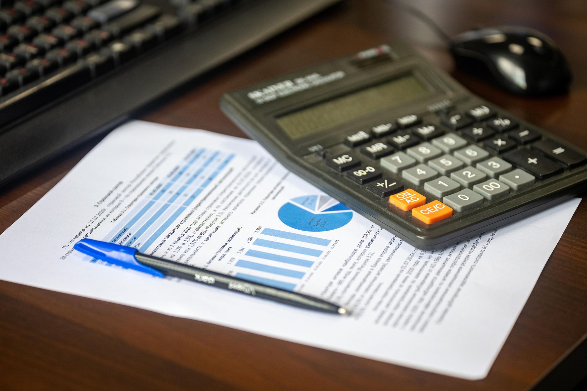 Economics for Business Mathematical — Desk with calculator, financial report, and pen, suggesting business analysis.