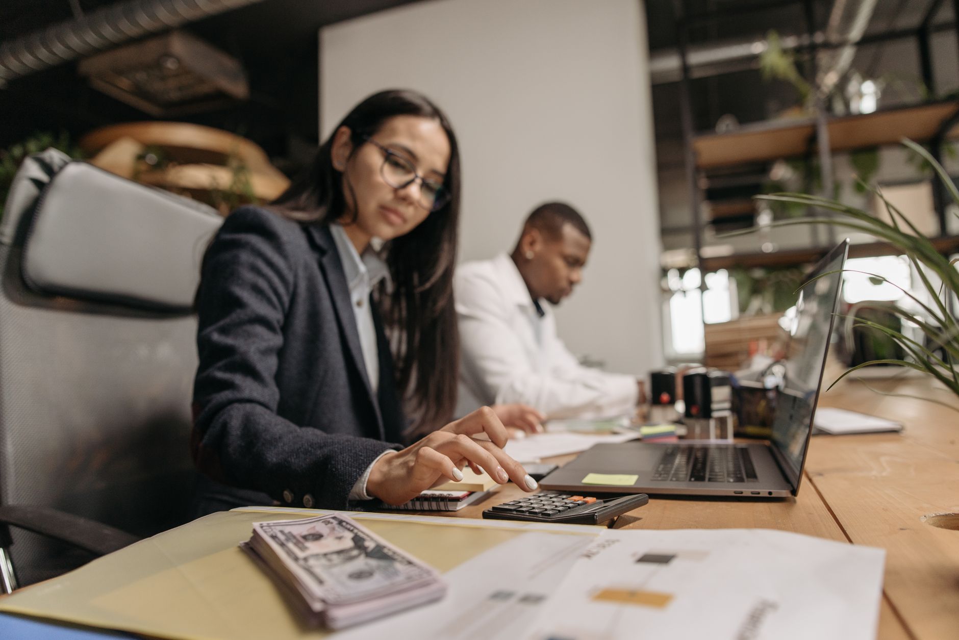 Financial Accounting — Two business professionals collaborating with a laptop and calculator in a modern office.