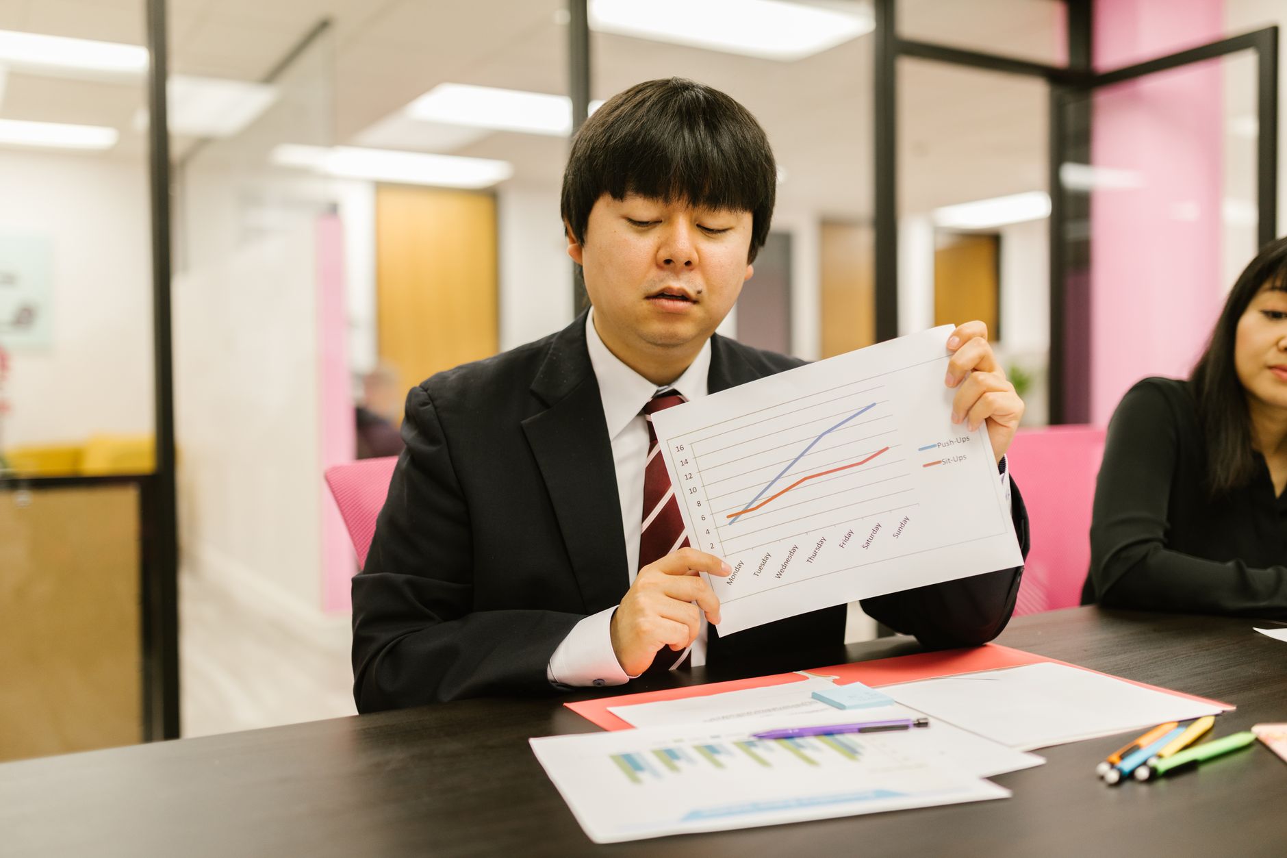 Financial Reporting — Two professionals in business attire discussing graphs during an office meeting.