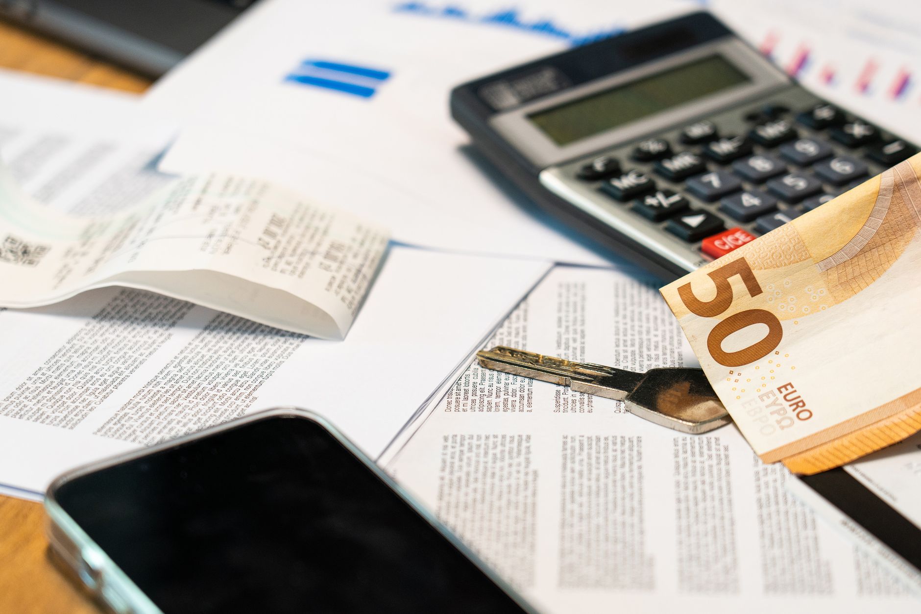 Accounting in a Business Context — Flat lay of financial documents, euro note, calculator, smartphone, and key for budget management.