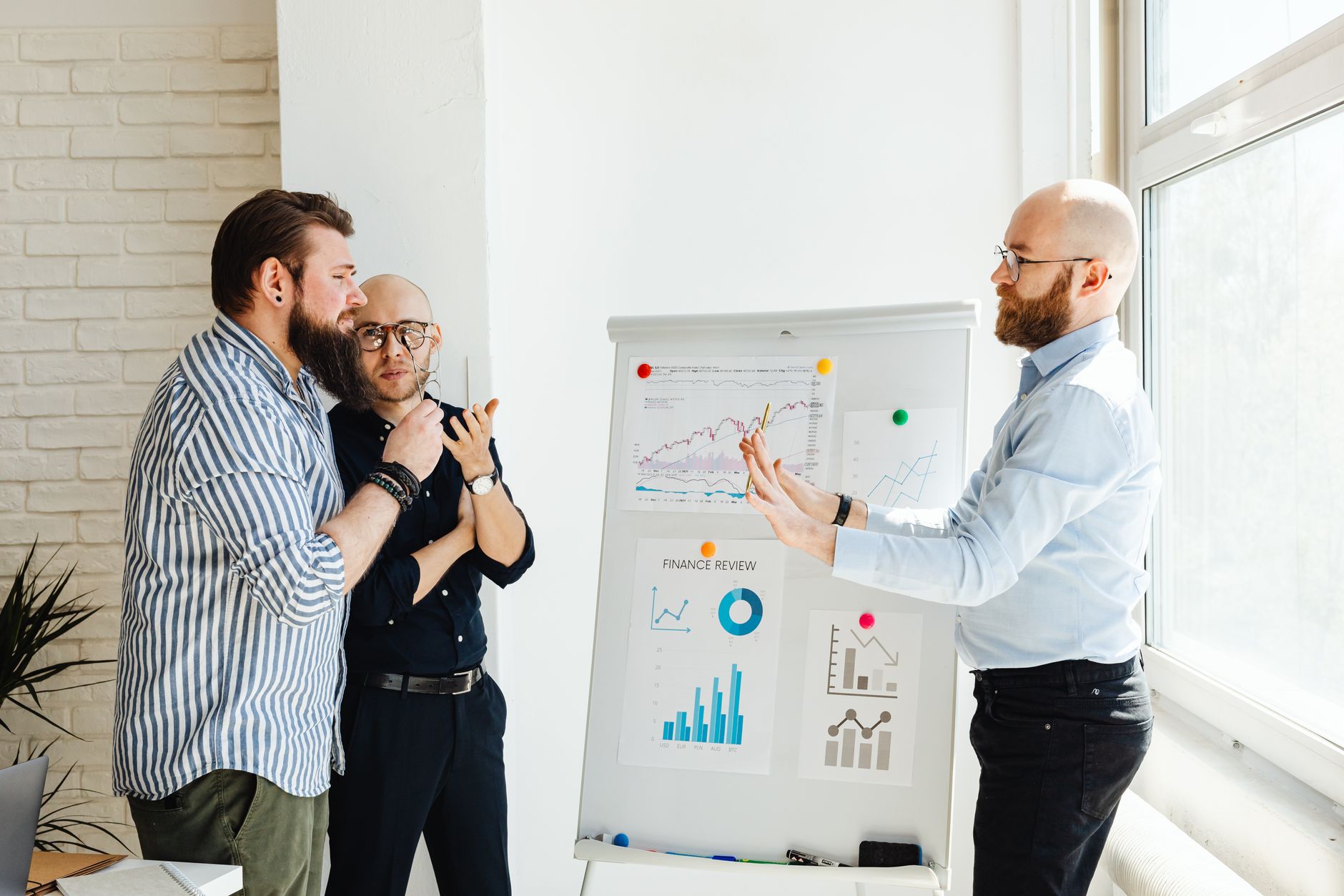 Leadership and Management in Accounting — Three professionals discussing financial charts and graphs during a business meeting.