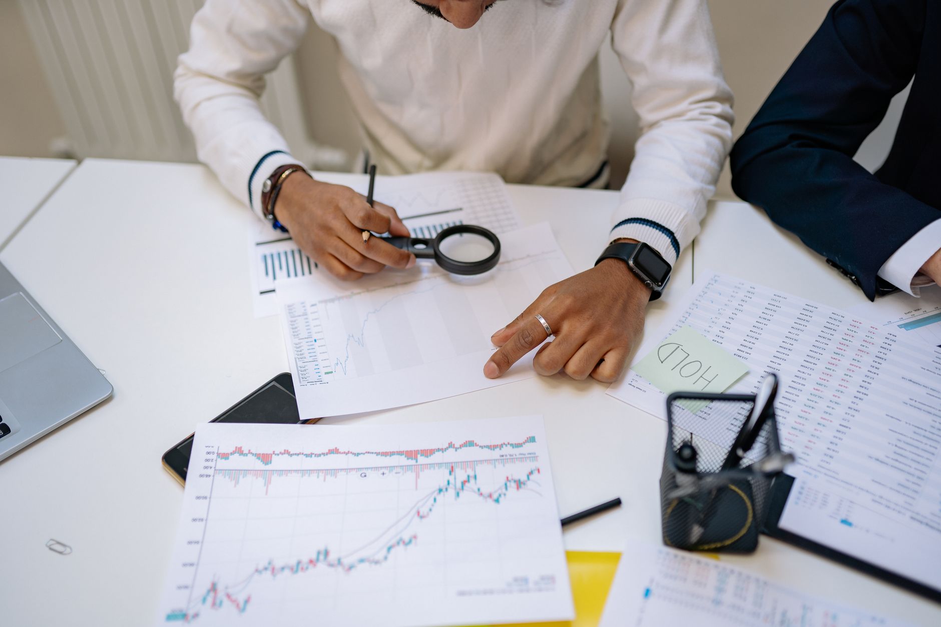 Financial Analyst — Business professionals reviewing charts with a magnifying glass in an office setting.