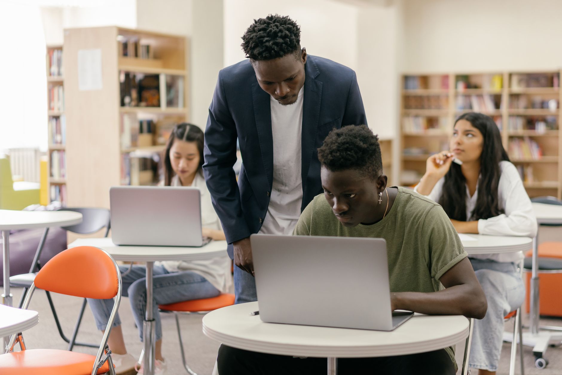 Inventory Lending — Students learning in a classroom setting with a teacher assisting and laptops on desks, creating an interactive education environment.
