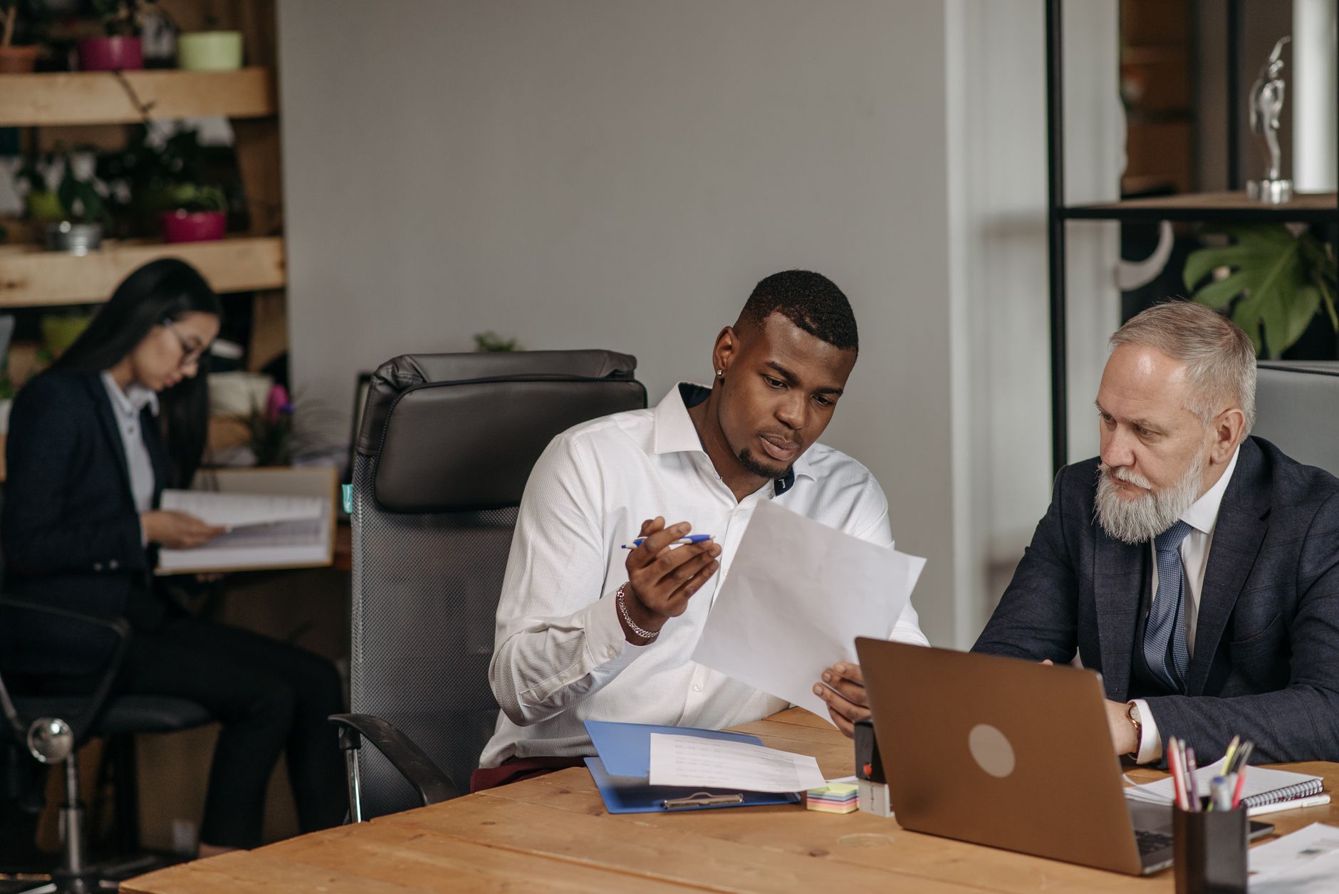 Account Management — Business professionals discussing documents in a modern office environment with focus on teamwork and collaboration.