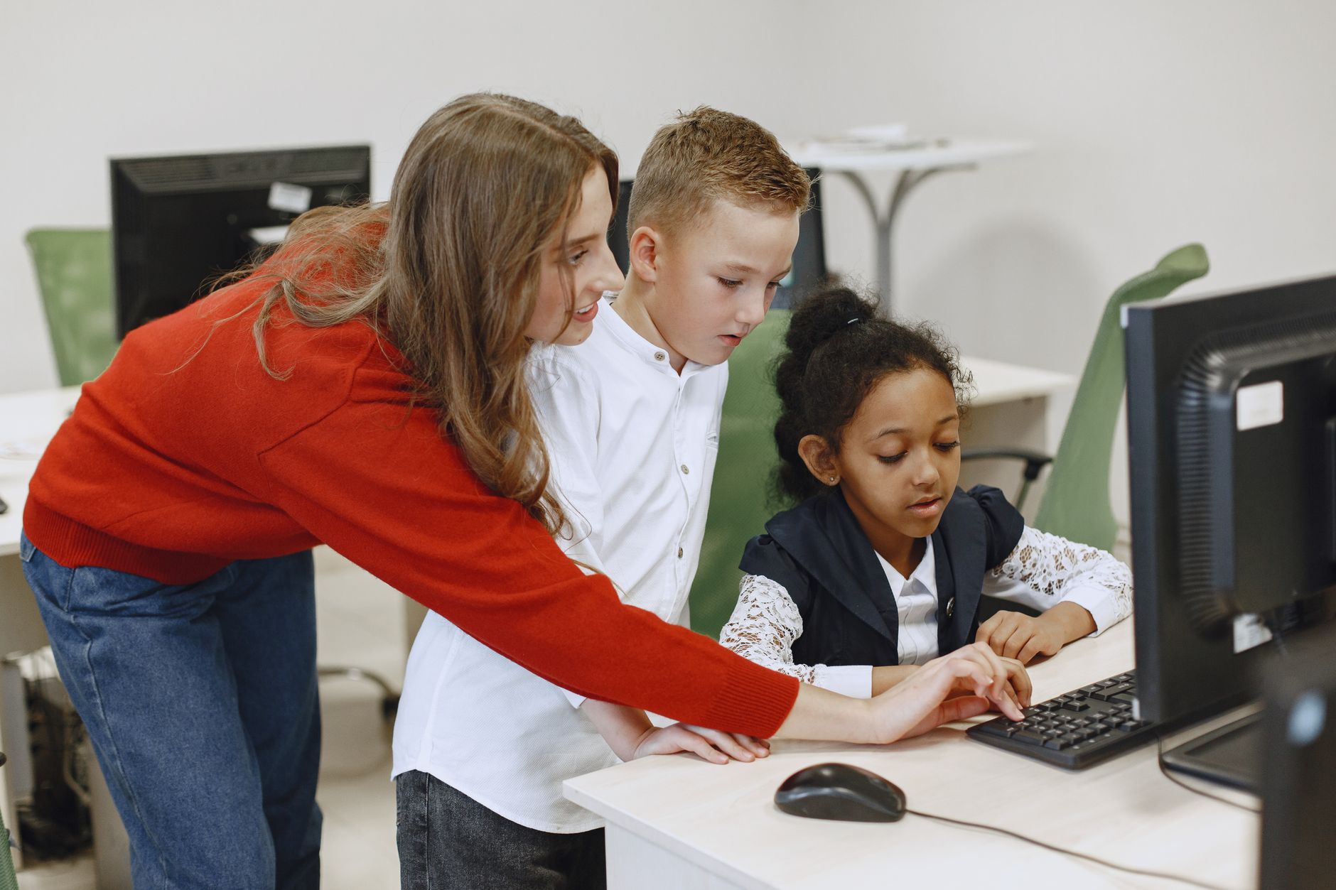 Equity and Trusts — Young teacher helps students with a computer task in a classroom setting.
