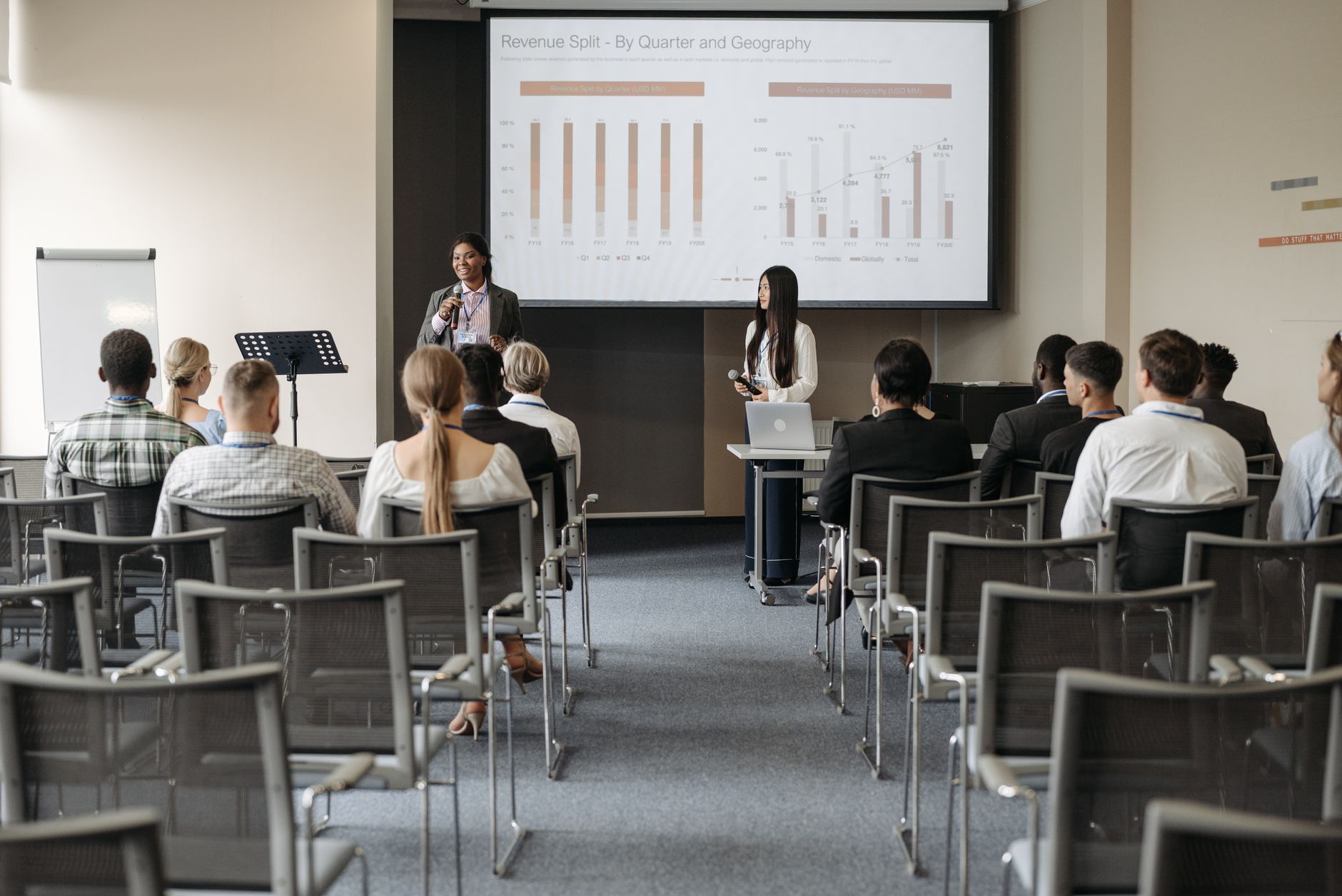 Physical IT Networking — Professional business seminar with audience listening to presenters sharing data insights.