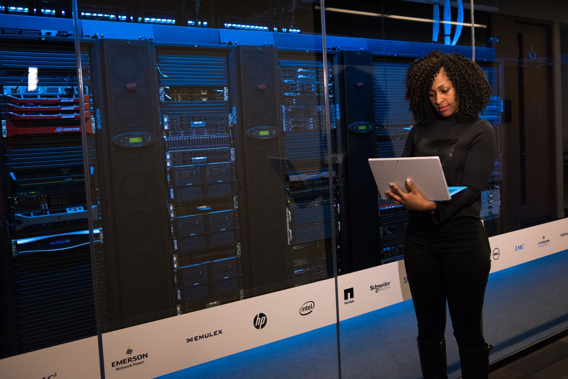 Mathematics and Statistics for ITPC Maintenance and Operating Systems — A female engineer using a laptop while monitoring data servers in a modern server room.
