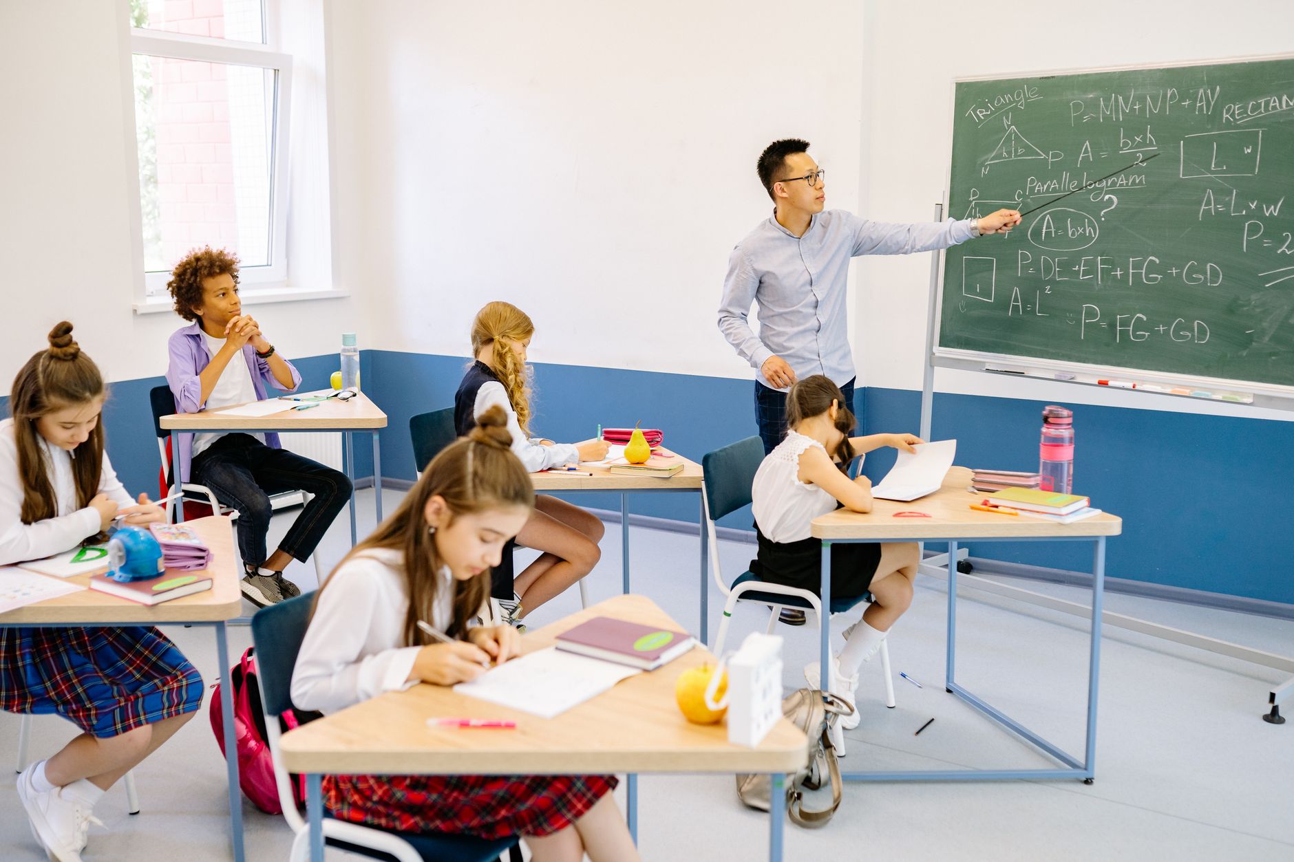 System Administration — Diverse classroom with teacher discussing mathematics, students engaged in learning.