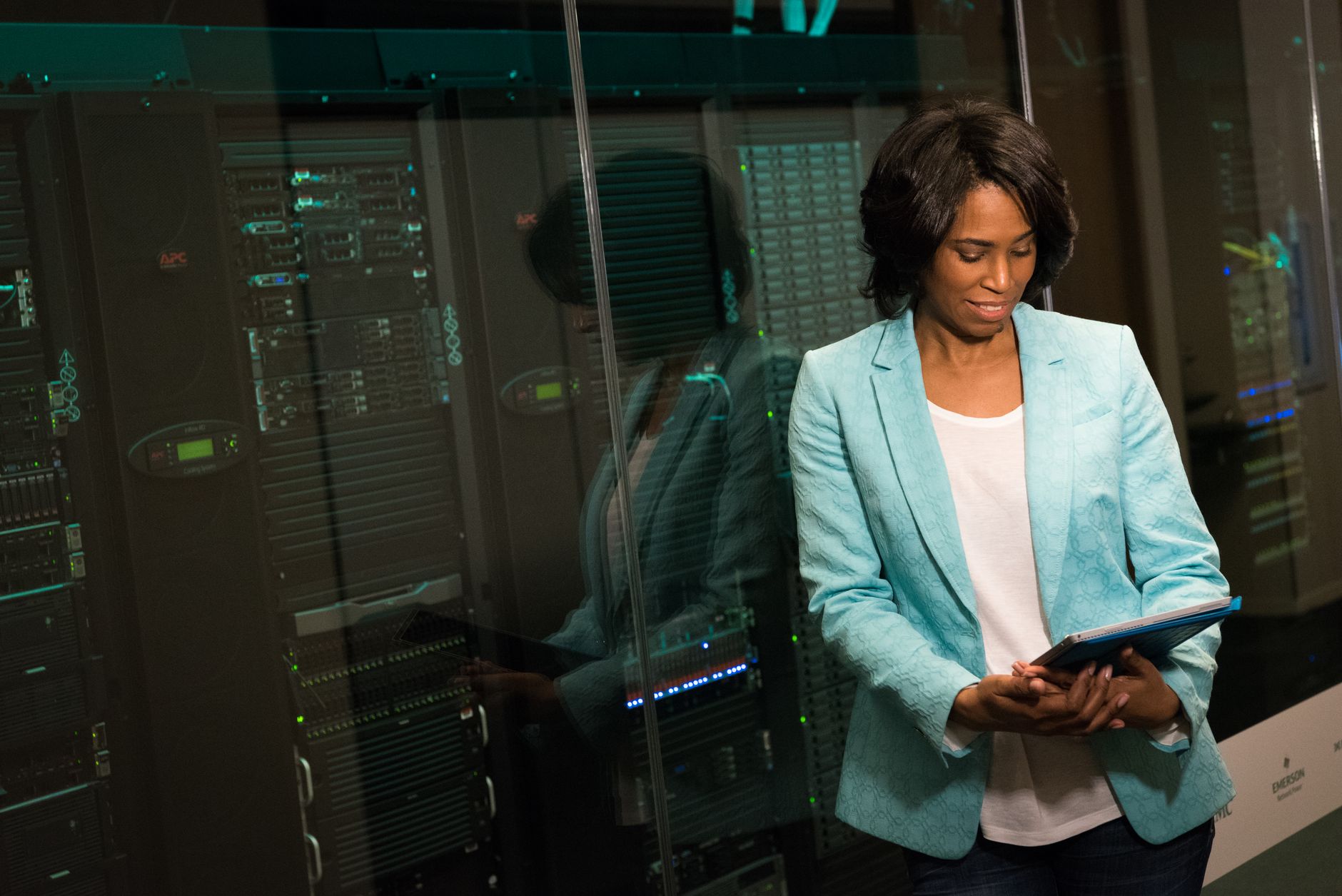 Network Design and Administration — Female it professional examining data servers in a modern data center setting.