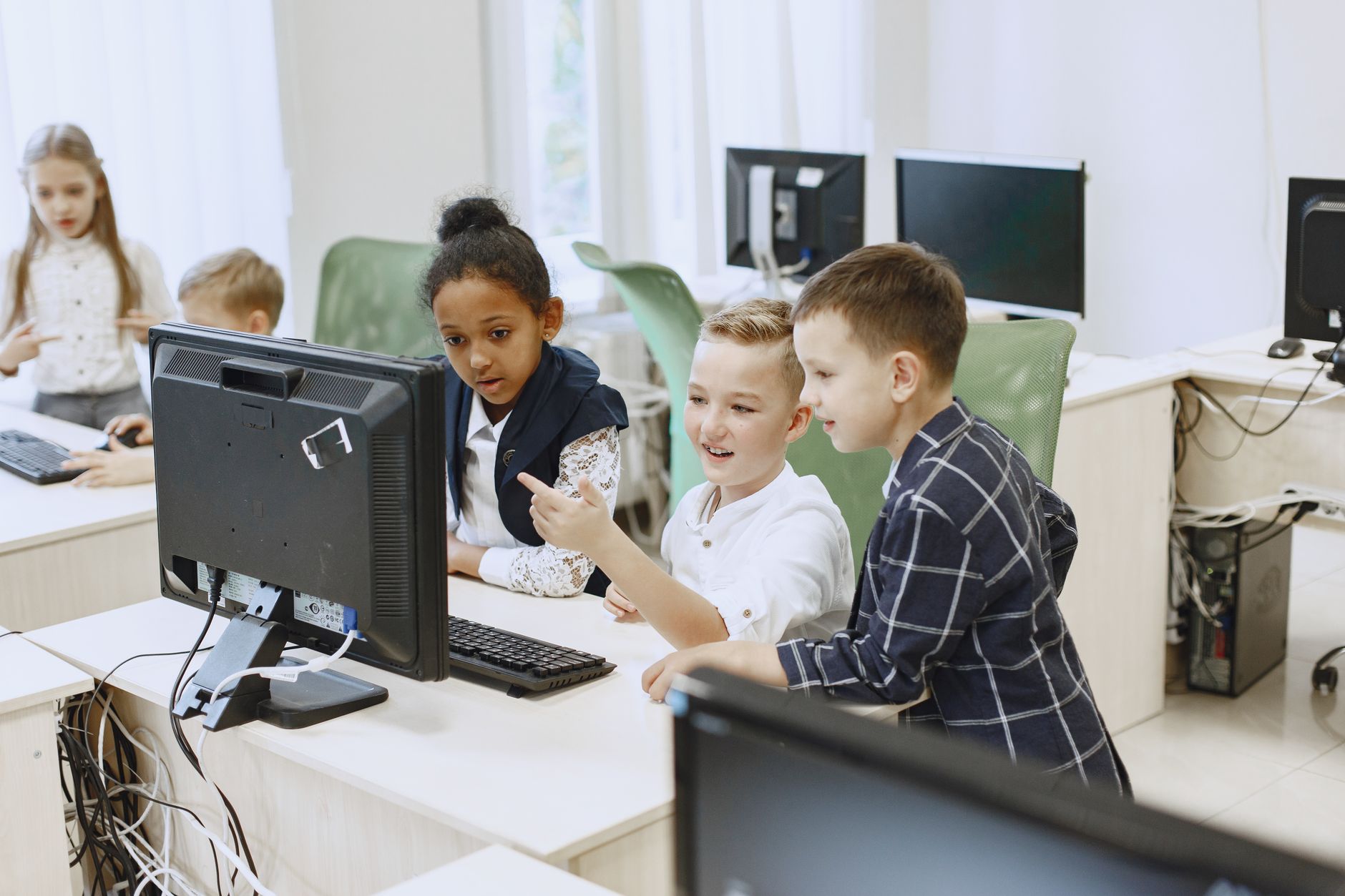 Network SecurityC#.NET Programming — Young students engaging with computers in a modern classroom setting.