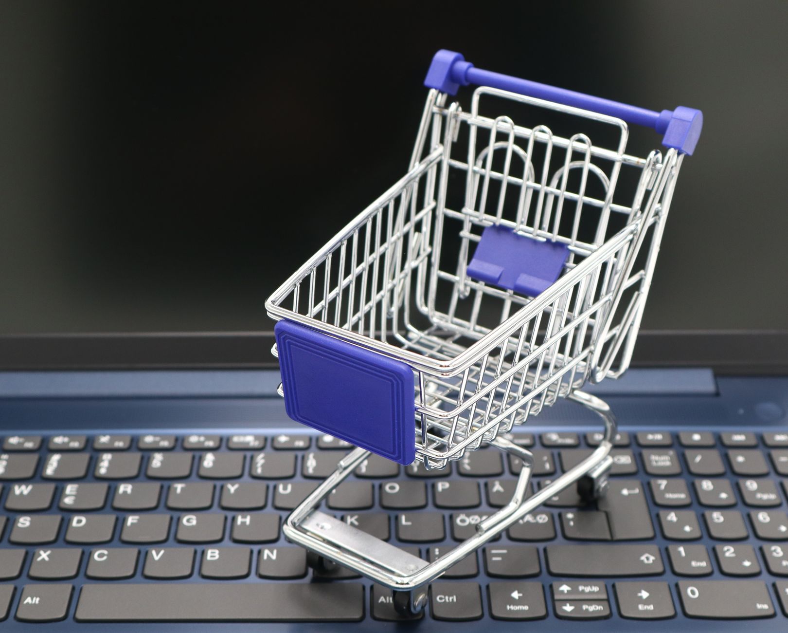 Business to Consumer (B2C) E-commerce — A mini shopping cart placed on a laptop keyboard, symbolizing online shopping and digital retail.