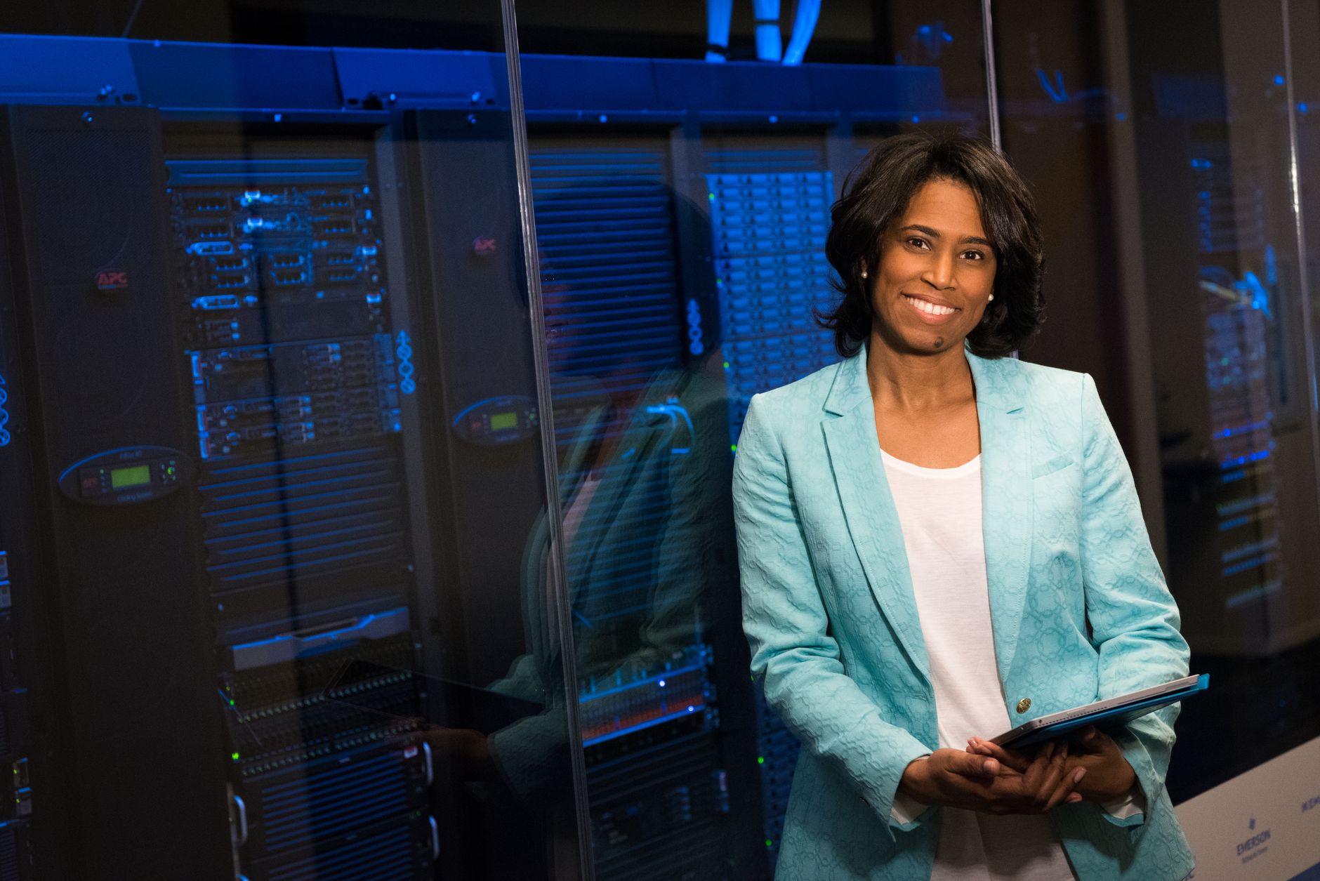Network Design and Administration — Smiling woman in data center showcasing technology expertise.