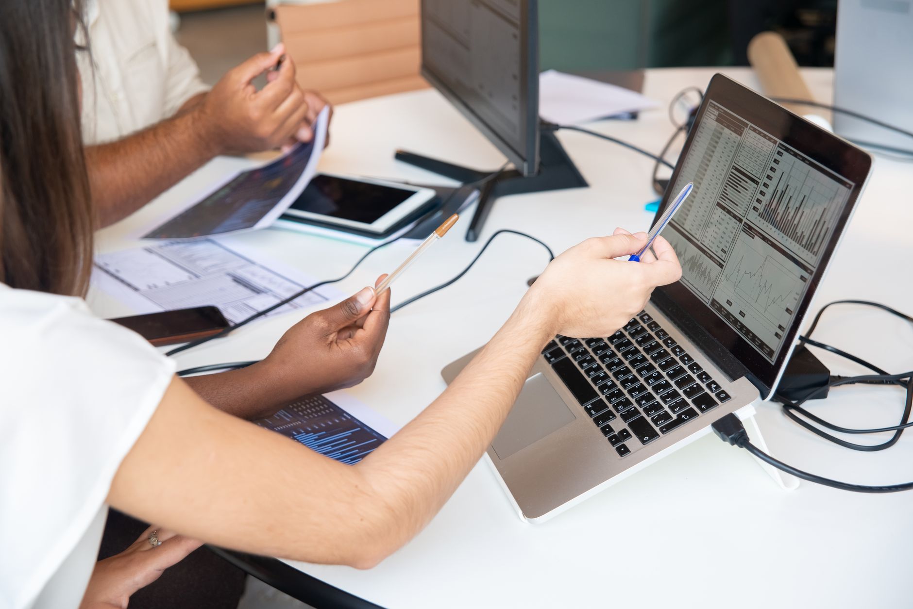 Fundamentals of Data Analytics — Professionals analyzing data charts on a laptop in an office setting, collaboratively discussing insights.
