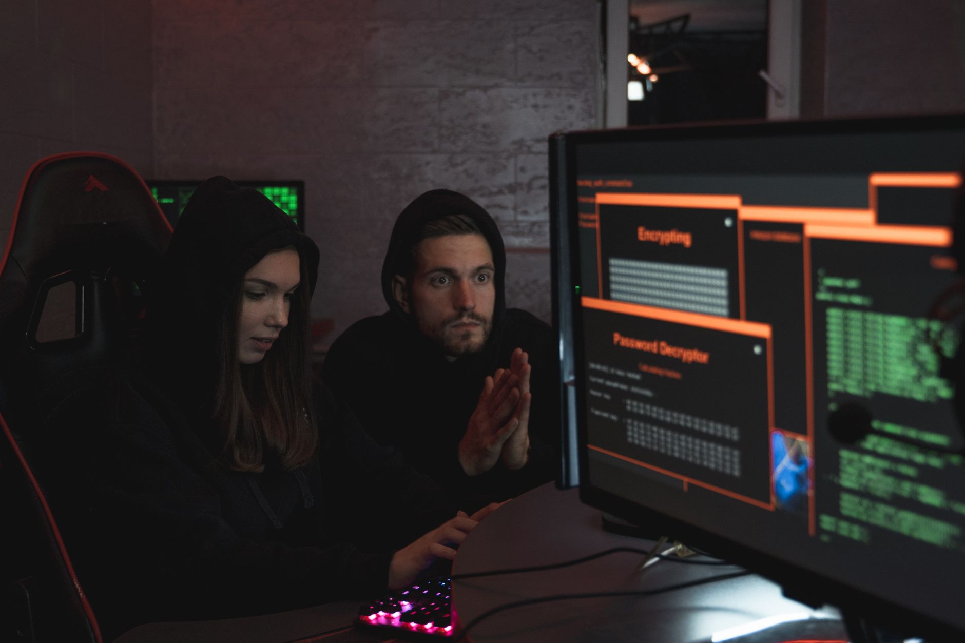 Threat and Risk: Expecting the Unexpected — Cybersecurity experts in hoodies analyzing encrypted data on computer screens in an indoor setting.