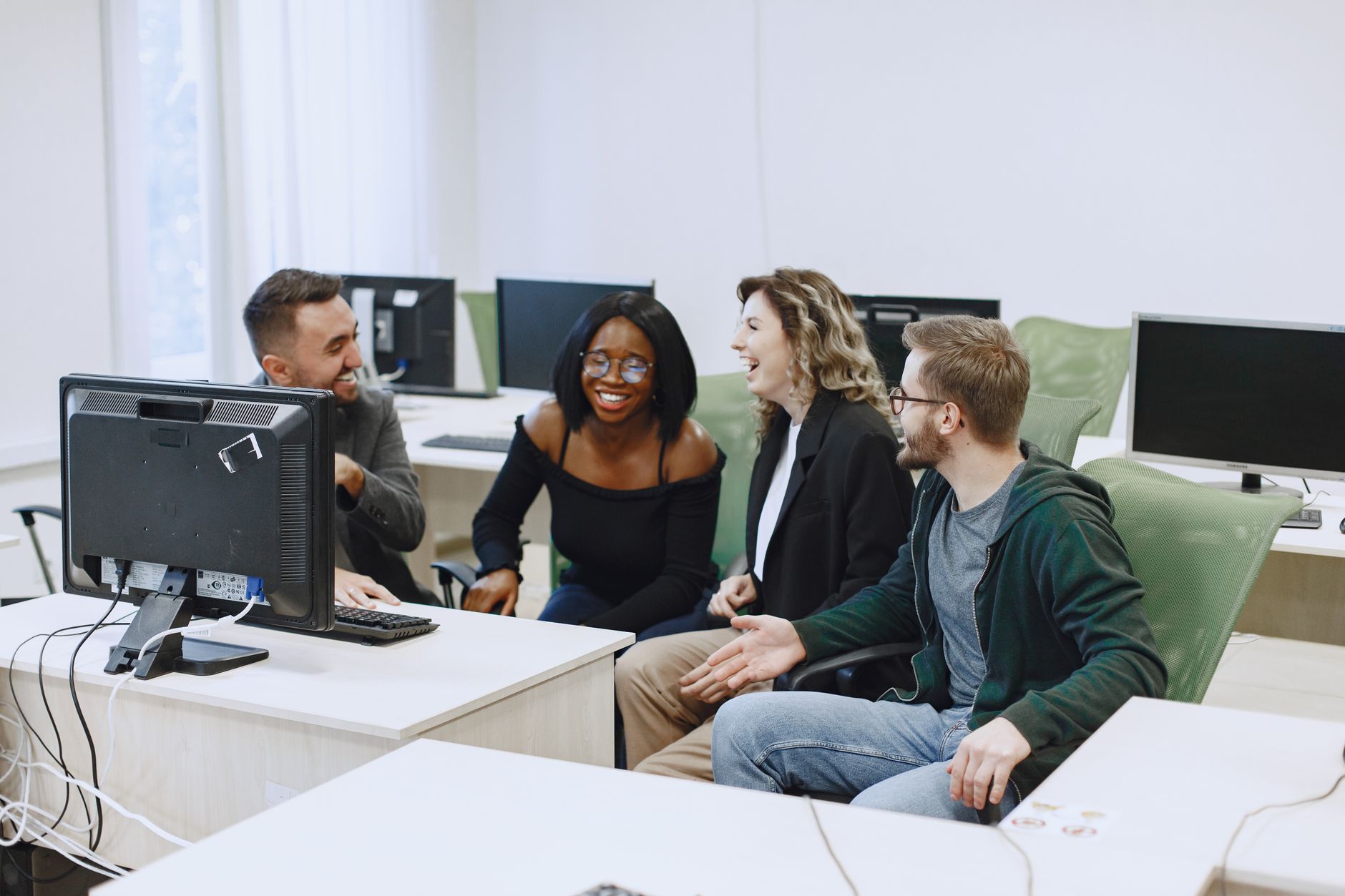 Security Strategy: Laws, Policies and Implementation — Diverse group of young adults collaborating and laughing in a computer lab.