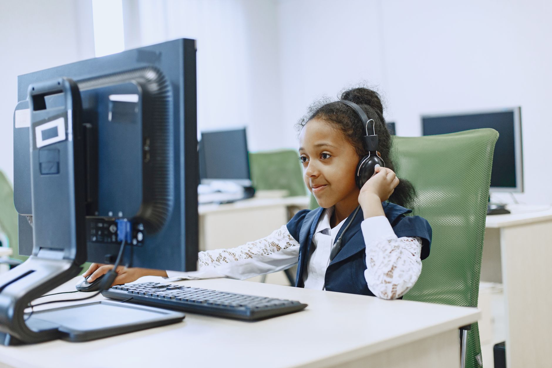 Critical Issues: Strategic Framework for Understanding Risk and Resilience Building — Smiling girl using computer in a modern lab setting, wearing a headset.