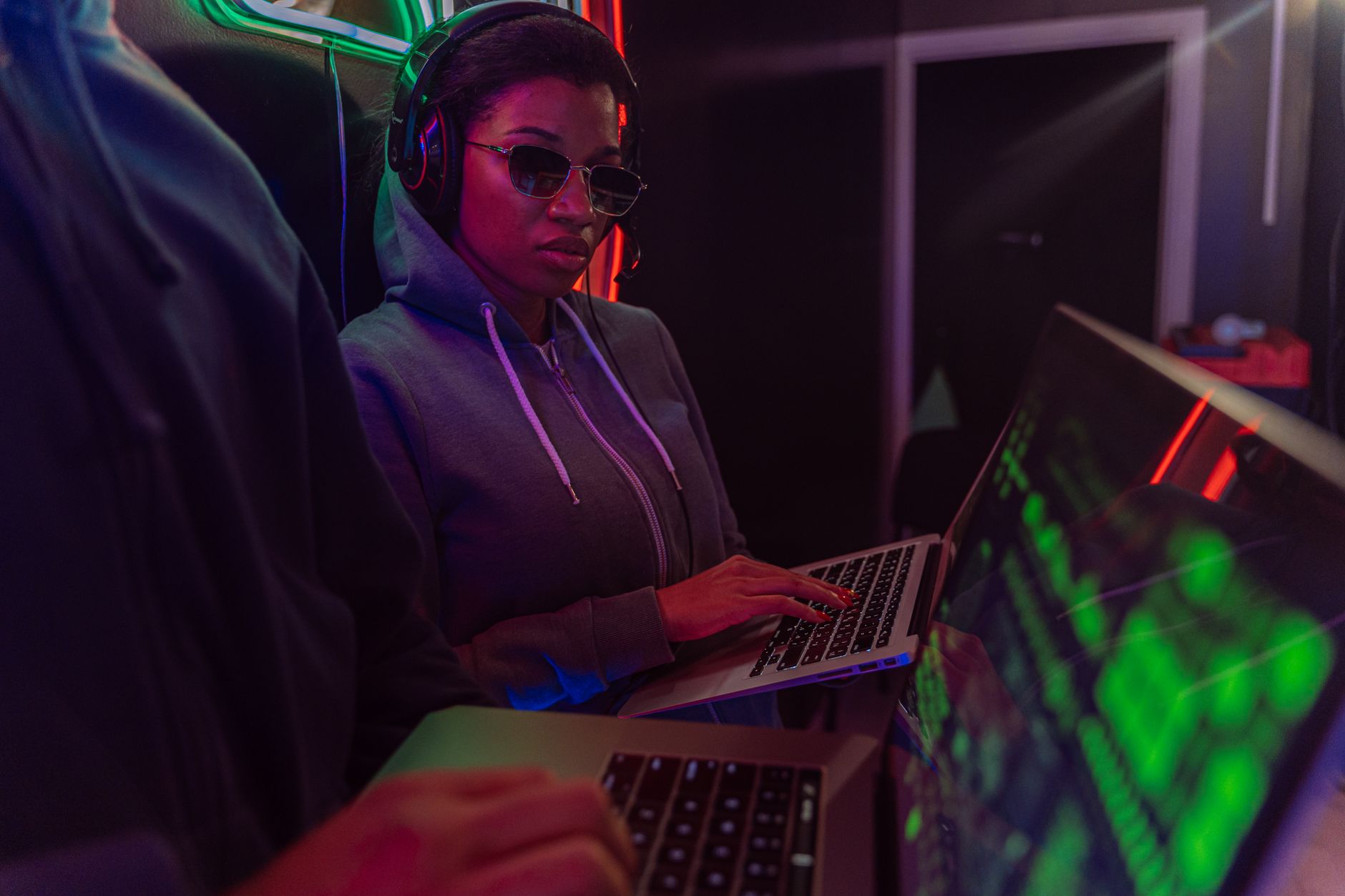 Critical Issues: Supply Chain Crime, Corruption and Terrorism — A tech-savvy adult using a laptop at night with neon lighting, creating a cyberpunk ambiance.
