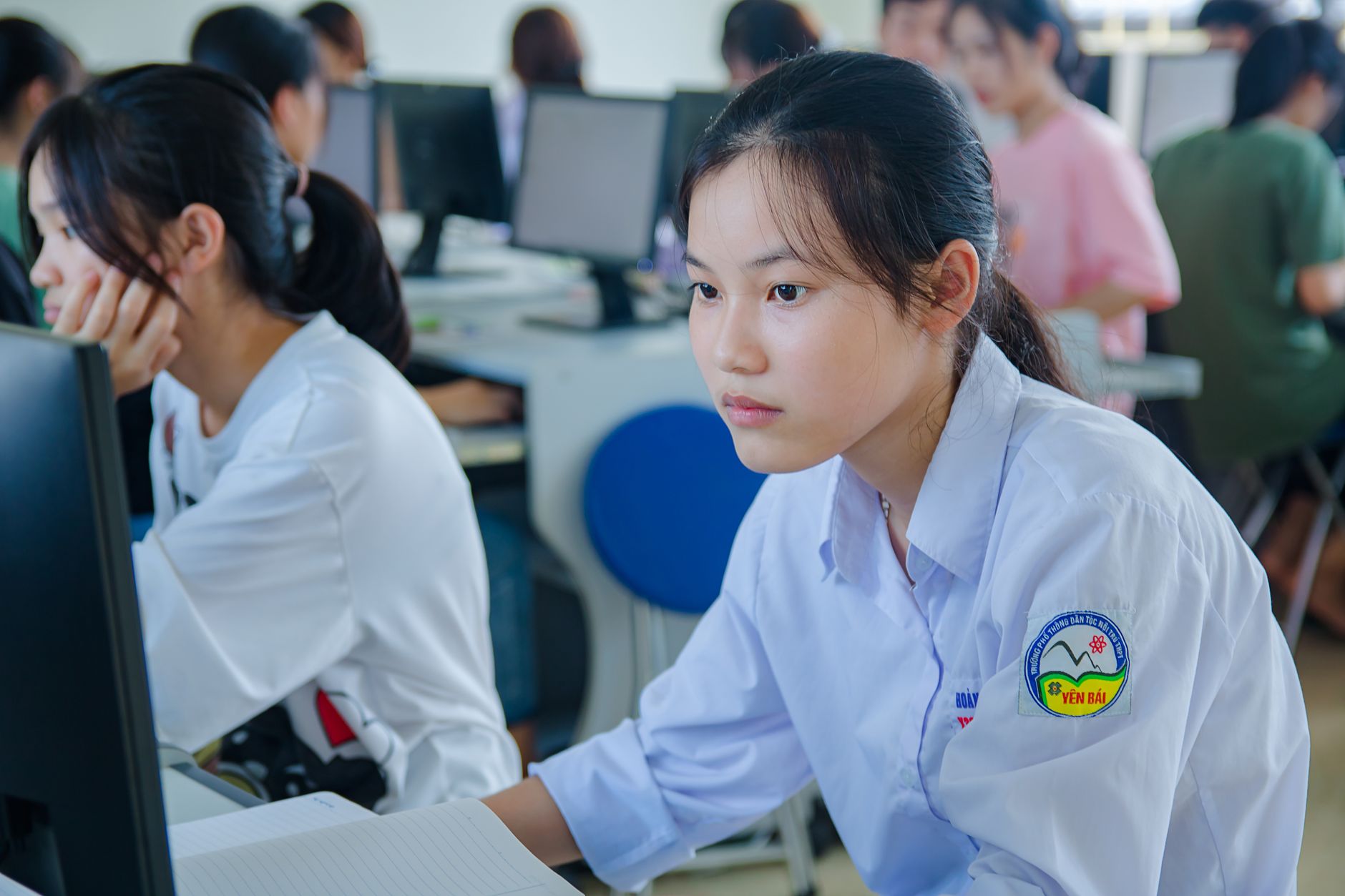 Supporting children with additional needs — Young students in uniform studying at computers for teamwork and education.