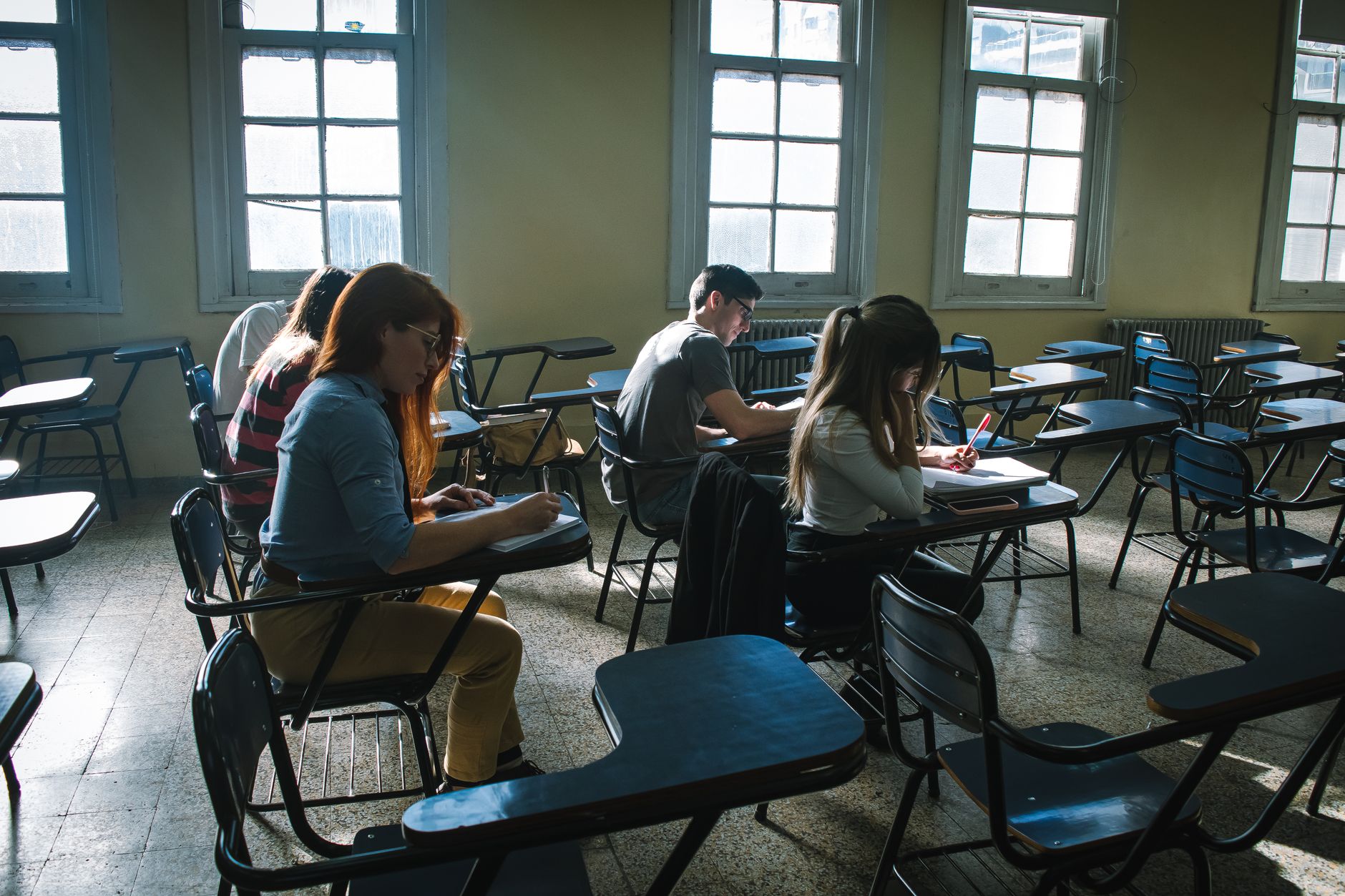 Managing children’s holistic development in early years — A group of students focused on taking a test in a sunlit classroom setting.