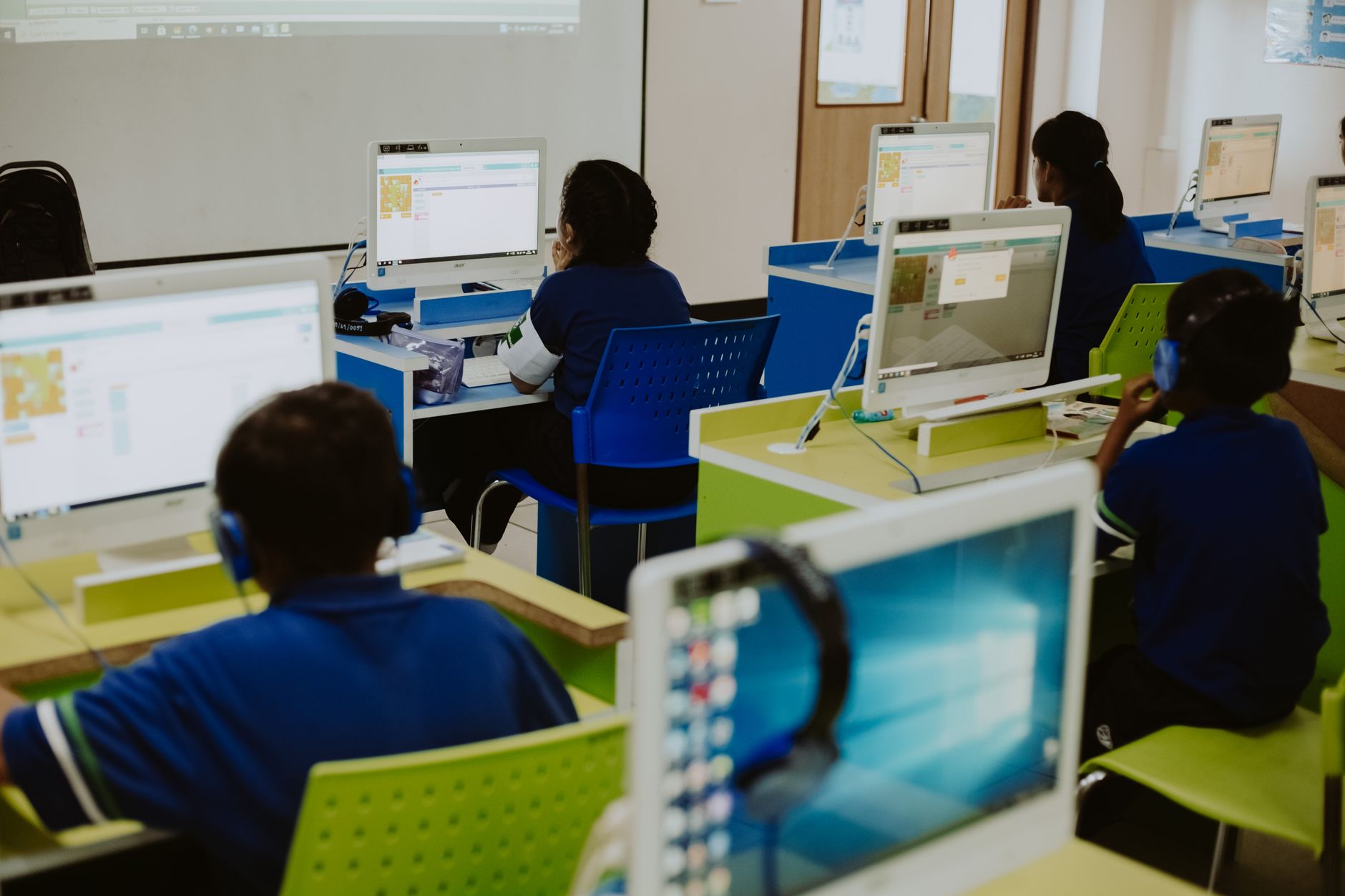 Developing children’s literacy skills — Children engaged in learning at computers in a modern classroom setting, promoting digital literacy.
