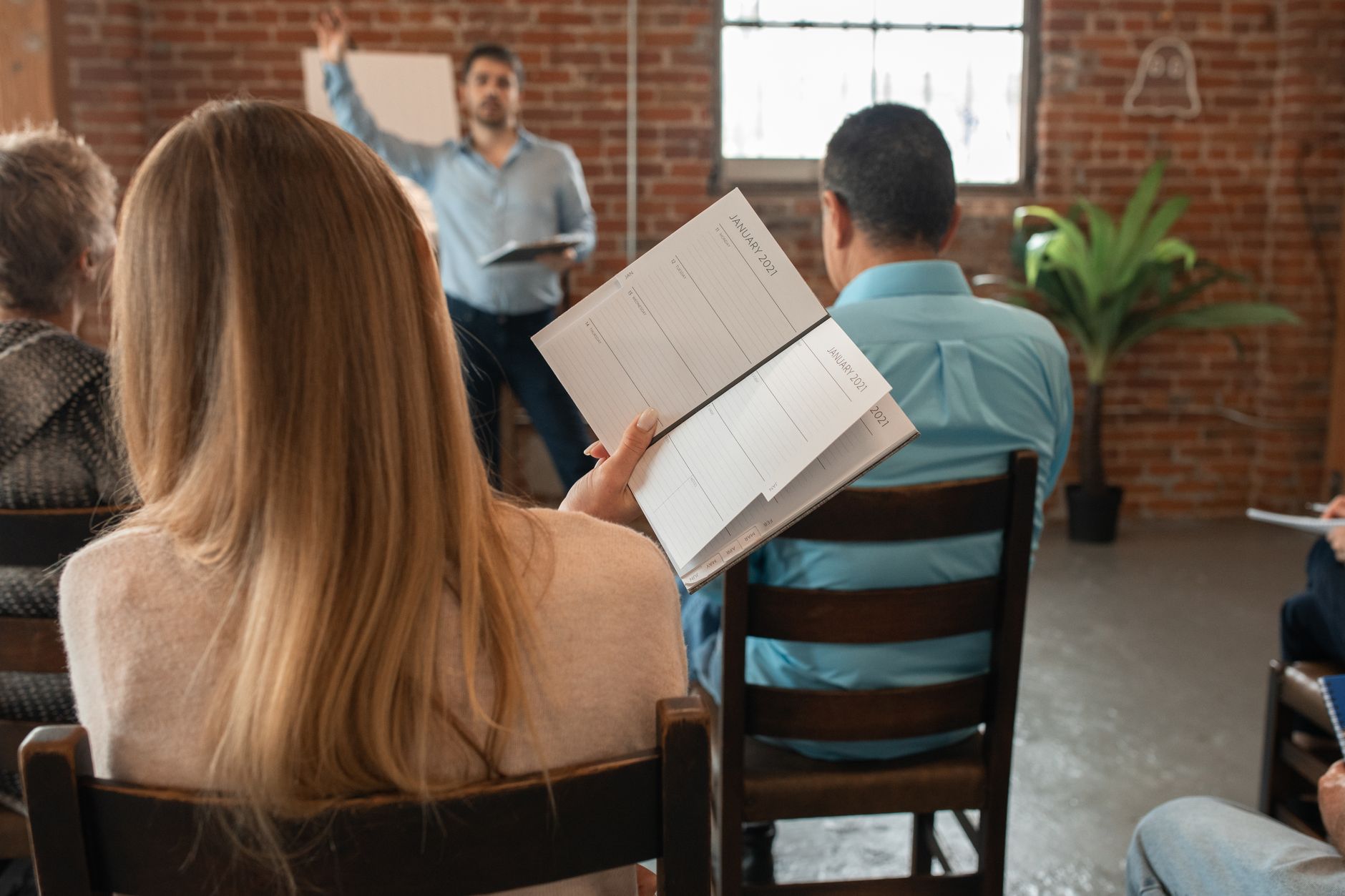 Professional Practice in Education and Training — Adult students in a classroom setting participating in interactive learning with notebooks in hand.