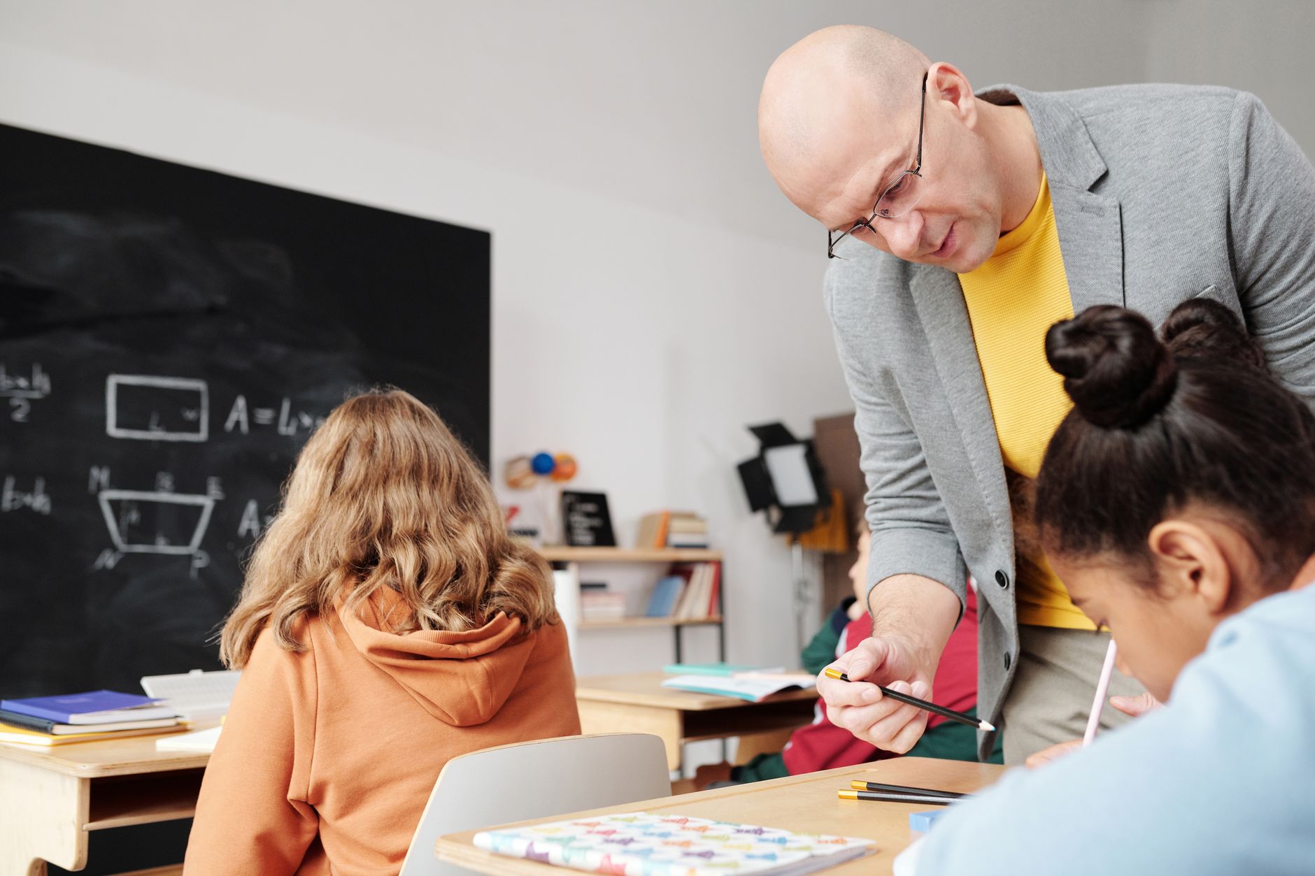 Engaging Learners — Teacher helping students in classroom, enhancing learning with personalized attention.